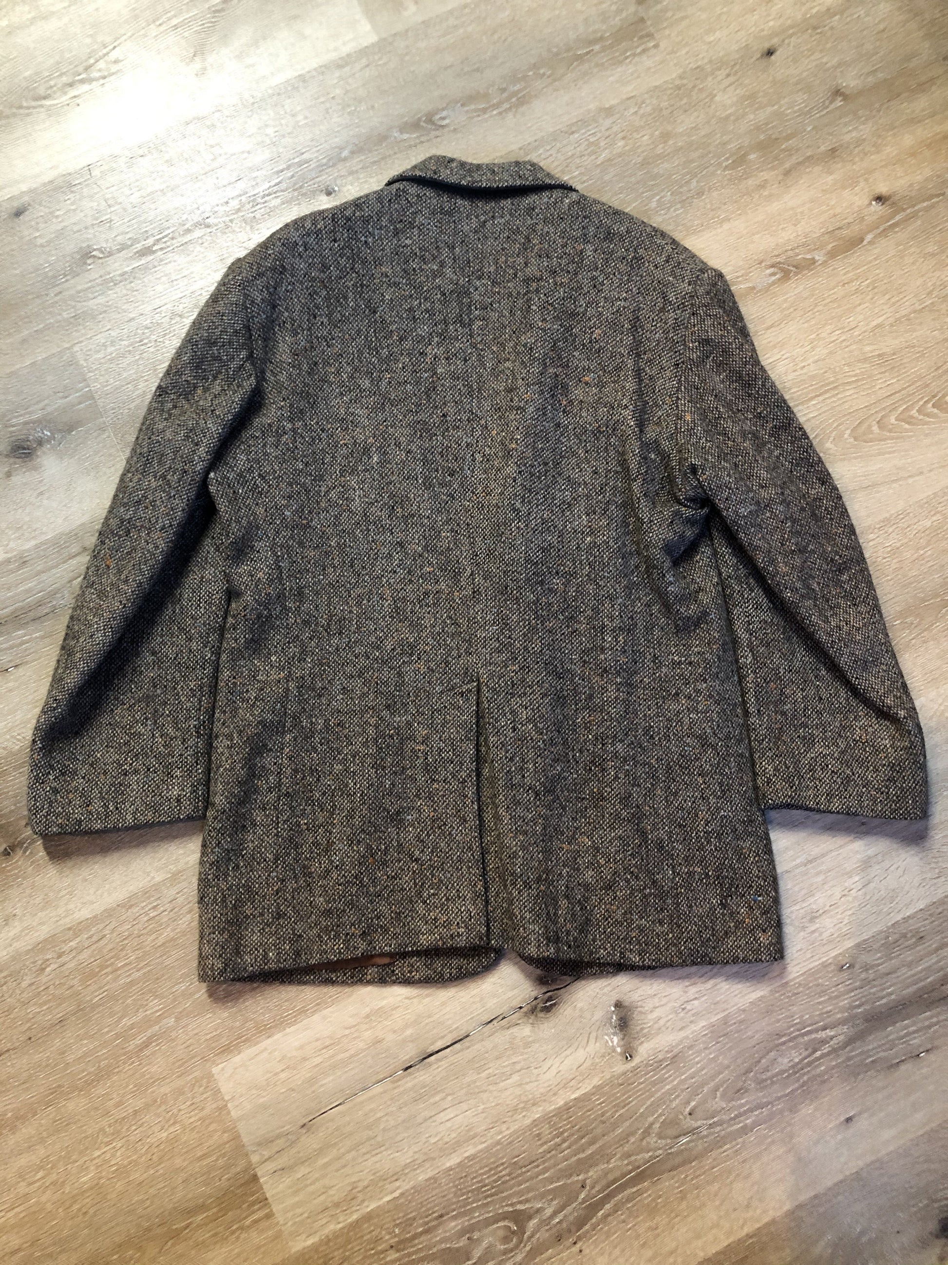 Kingspier Vintage - Donegal handwoven grey with blue and orange flecks 100% wool tweed jacket. This jacket is a two button, notch lapel with two patch pockets, a breast pocket and two inside pockets and a “this I defend” emblem embroidered on the chest. Made in Ireland.