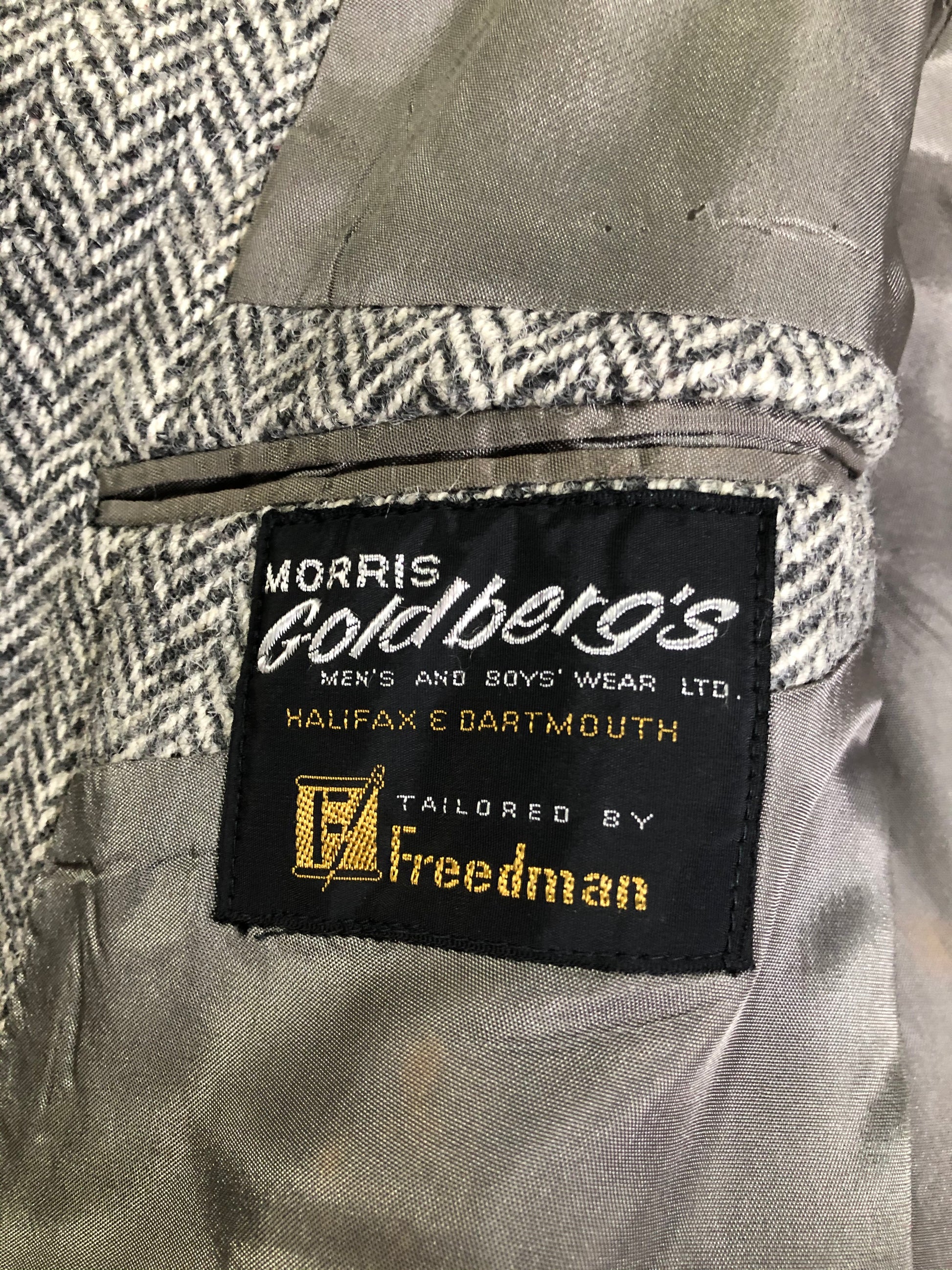 Kingspier Vintage - Morris Goldberg’s grey herringbone 100% wool tweed jacket. This jacket is a two button, notch lapel with two flap pockets, a breast pocket and three inside pockets. Made in Halifax, Nova Scotia.
