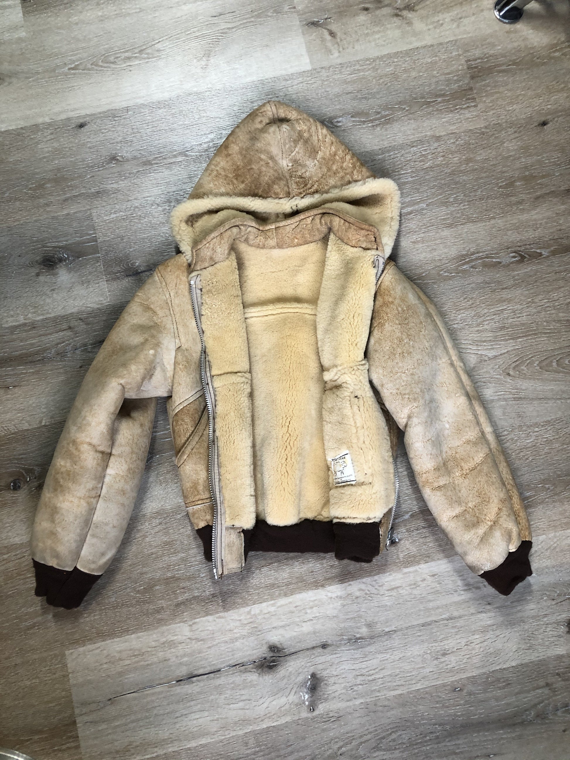 Kingspier Vintage - Ewe Wear, genuine sheepskin hooded bomber style jacket. This jacket features shearling lining, hood, zipper closure and slash pockets. Made in Kingston, Nova Scotia. Size XS.