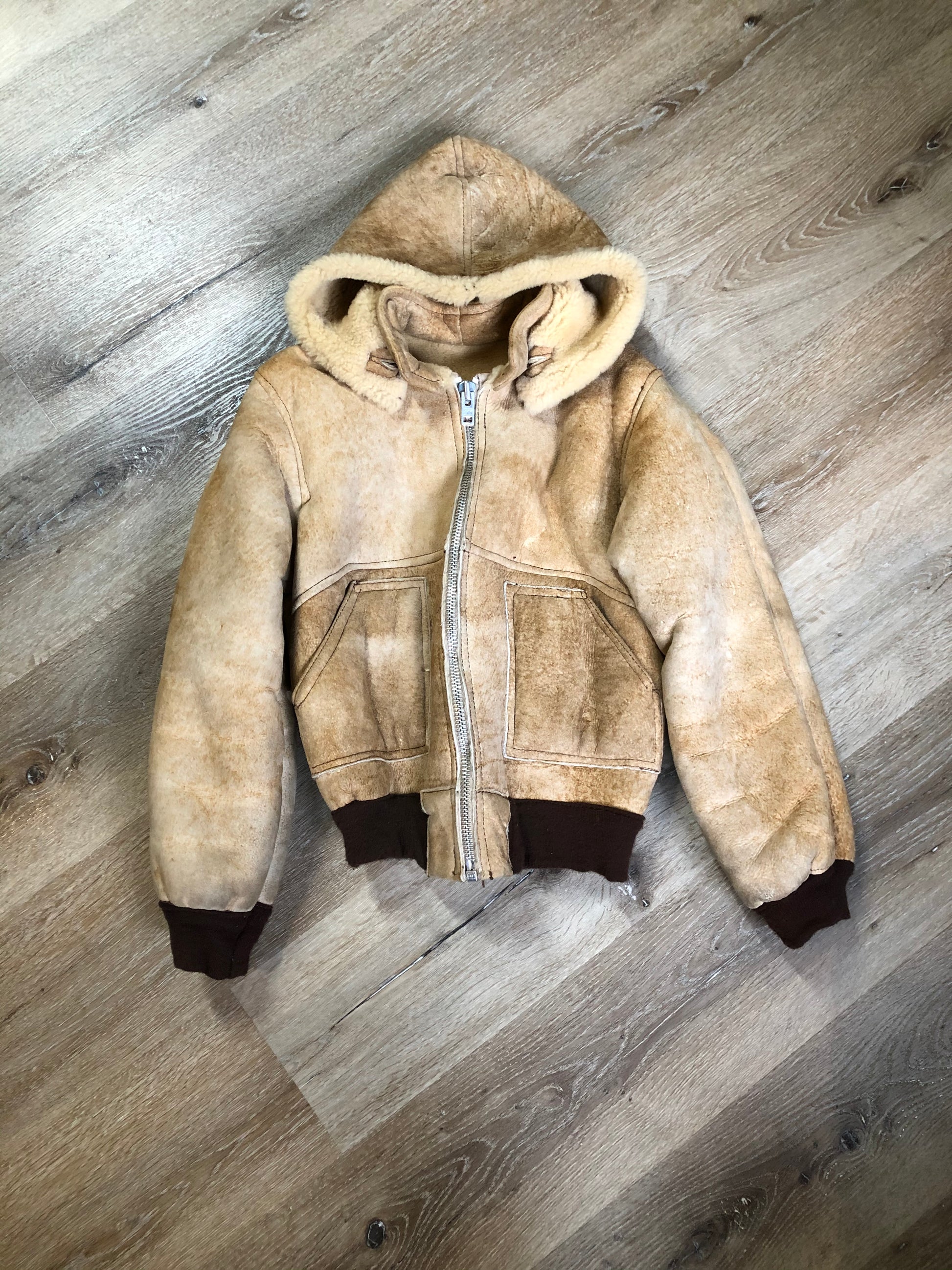 Kingspier Vintage - Ewe Wear, genuine sheepskin hooded bomber style jacket. This jacket features shearling lining, hood, zipper closure and slash pockets. Made in Kingston, Nova Scotia. Size XS.