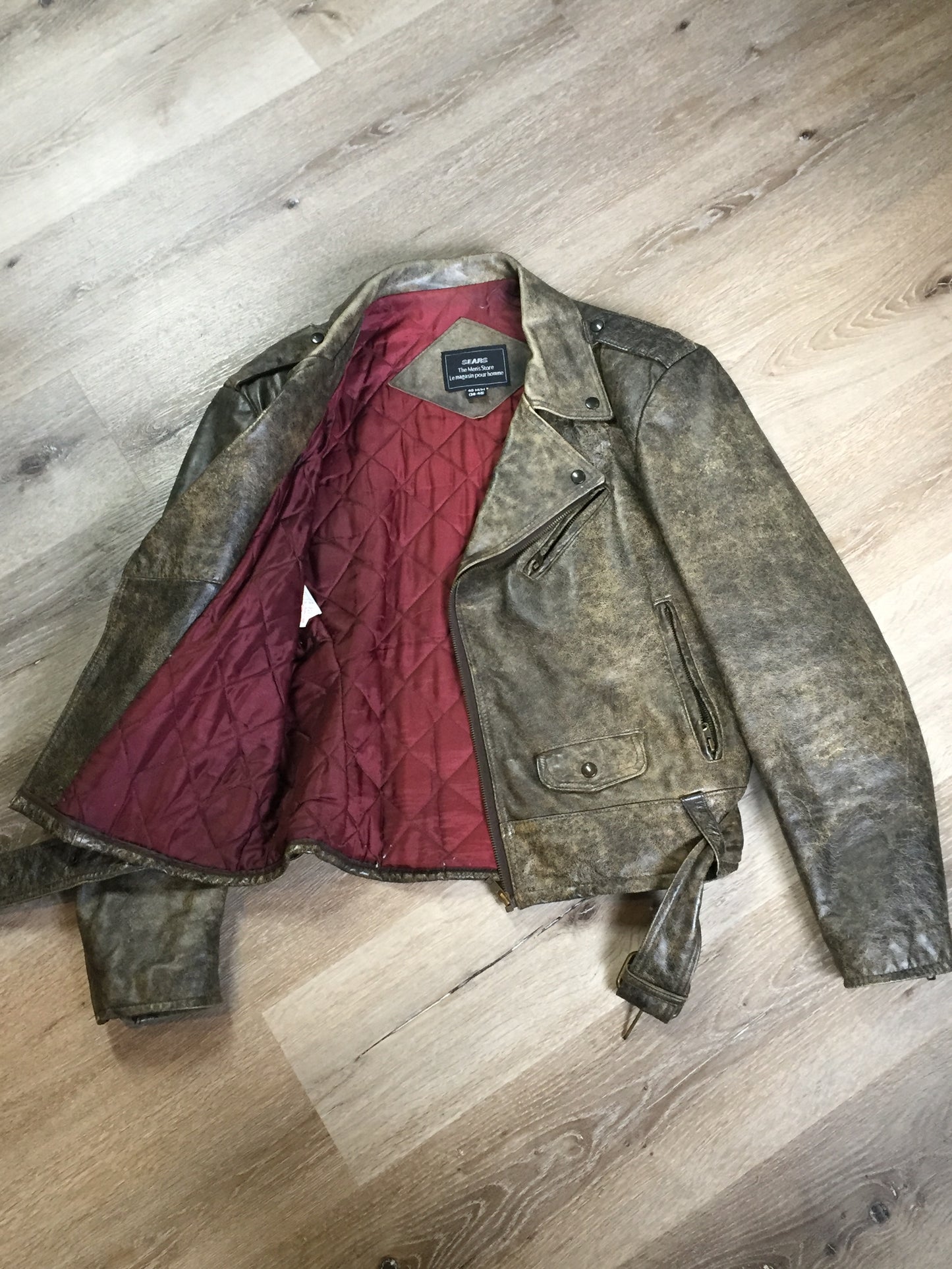 Kingspier Vintage - Sears distressed brown leather motorcycle jacket with zipper, two vertical zip pockets, one flap pocket and a slash pocket on the chest, a belt at the waist and red quilted lining. Size medium.