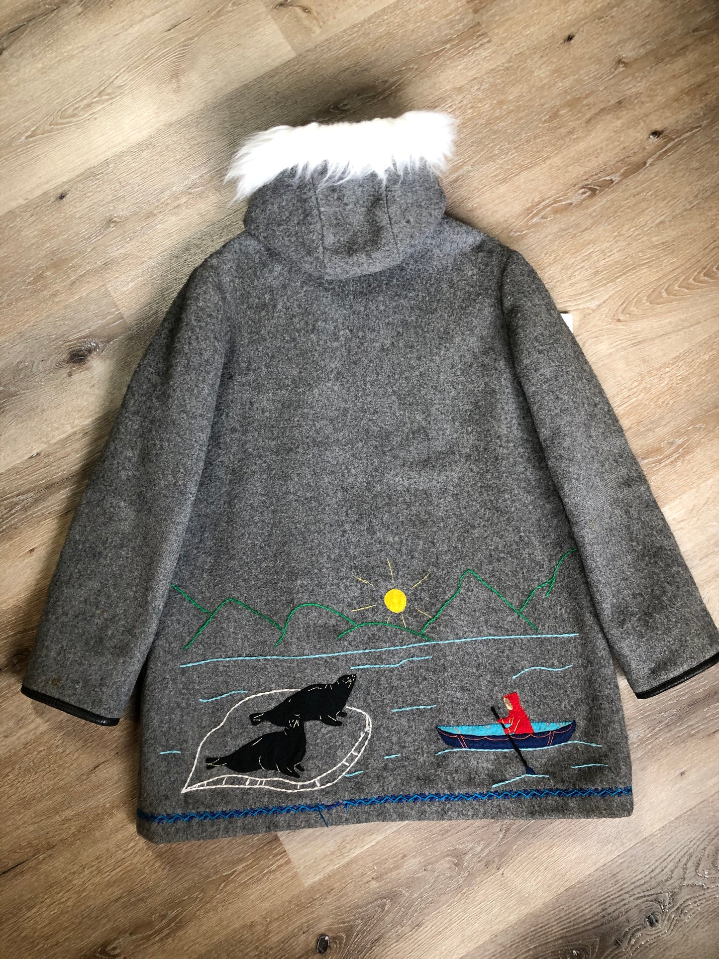 Kingspier Vintage - James Bay pure virgin wool northern parka in grey. This parka features a hood with white faux fur trim, zipper closure, quilted lining, knit inside hidden cuffs, hand stitched detail around the patch pockets and hem, felt seal appliqués in the front and a lovely arctic landscape on the back. Made in Canada.