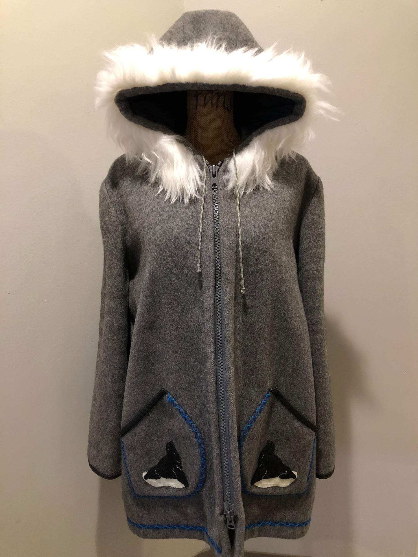 Kingspier Vintage - James Bay pure virgin wool northern parka in grey. This parka features a hood with white faux fur trim, zipper closure, quilted lining, knit inside hidden cuffs, hand stitched detail around the patch pockets and hem, felt seal appliqués in the front and a lovely arctic landscape on the back. Made in Canada.