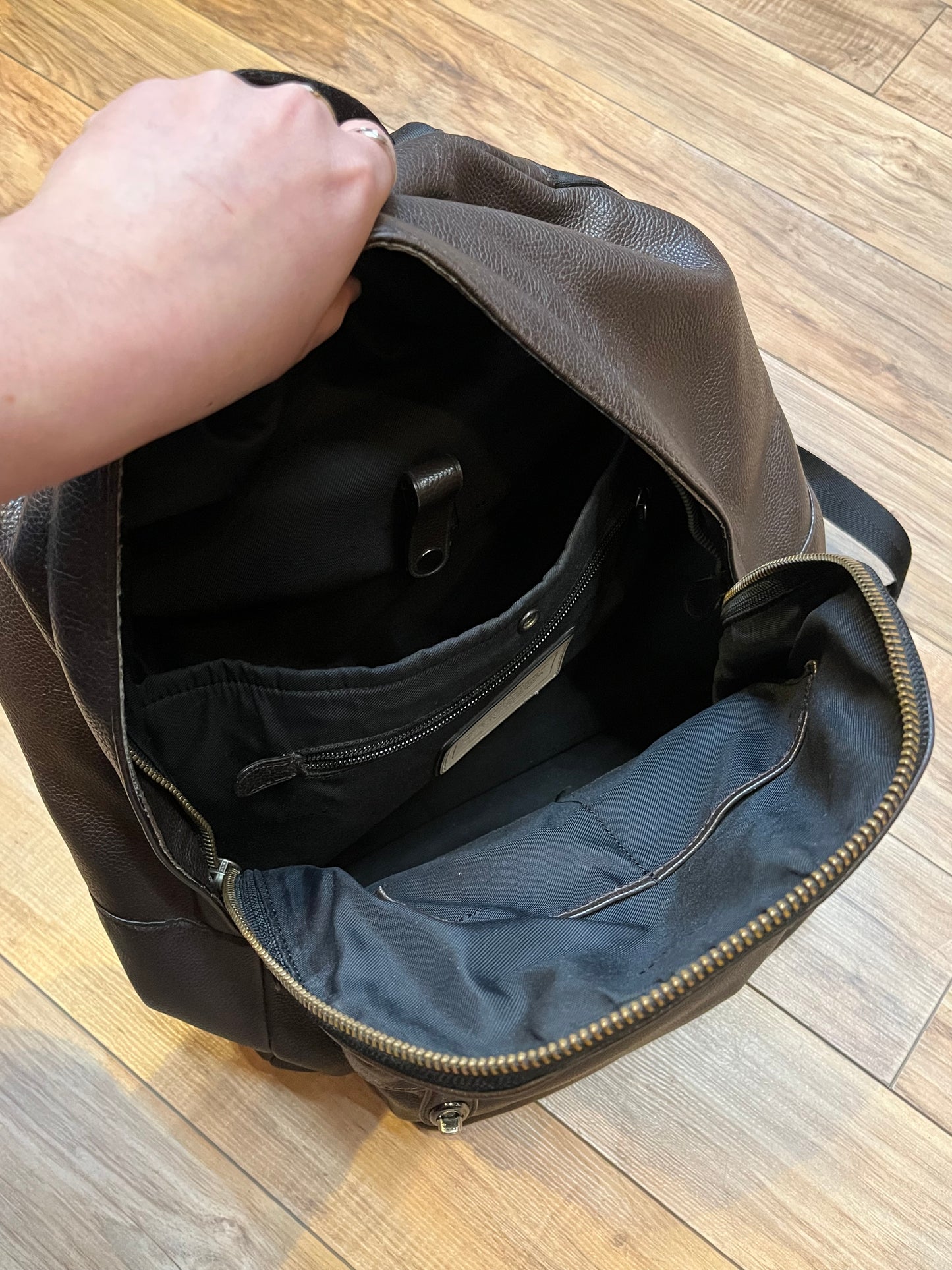 Authentic Coach brown pebble leather knapsack with adjustable shoulder straps, multiple pockets inside the large main compartment and one small compartment on the front with turn key detail.