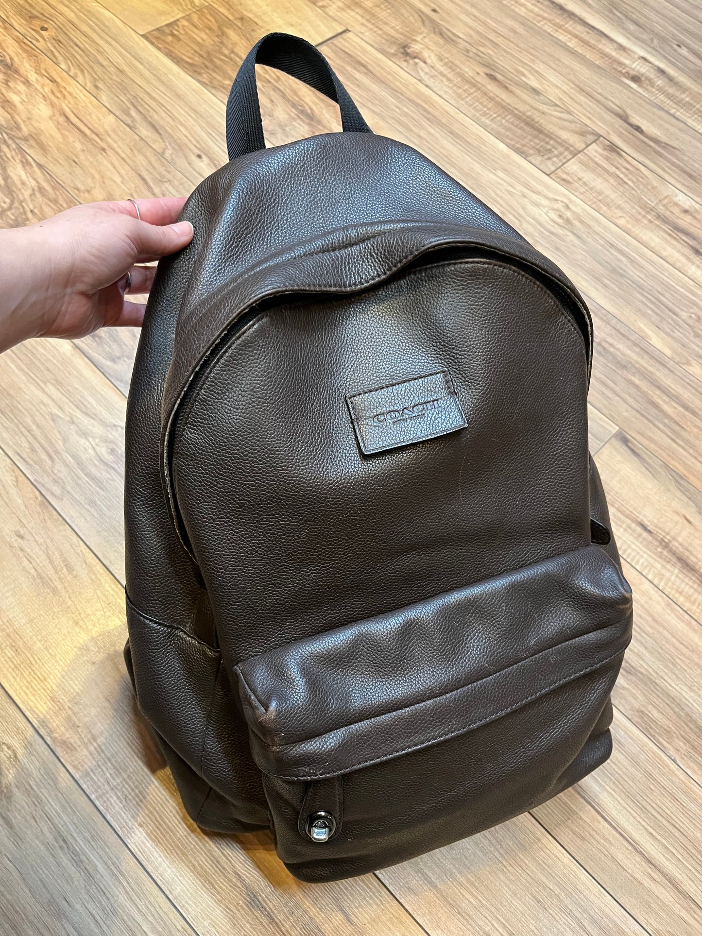 Authentic Coach brown pebble leather knapsack with adjustable shoulder straps, multiple pockets inside the large main compartment and one small compartment on the front with turn key detail.
