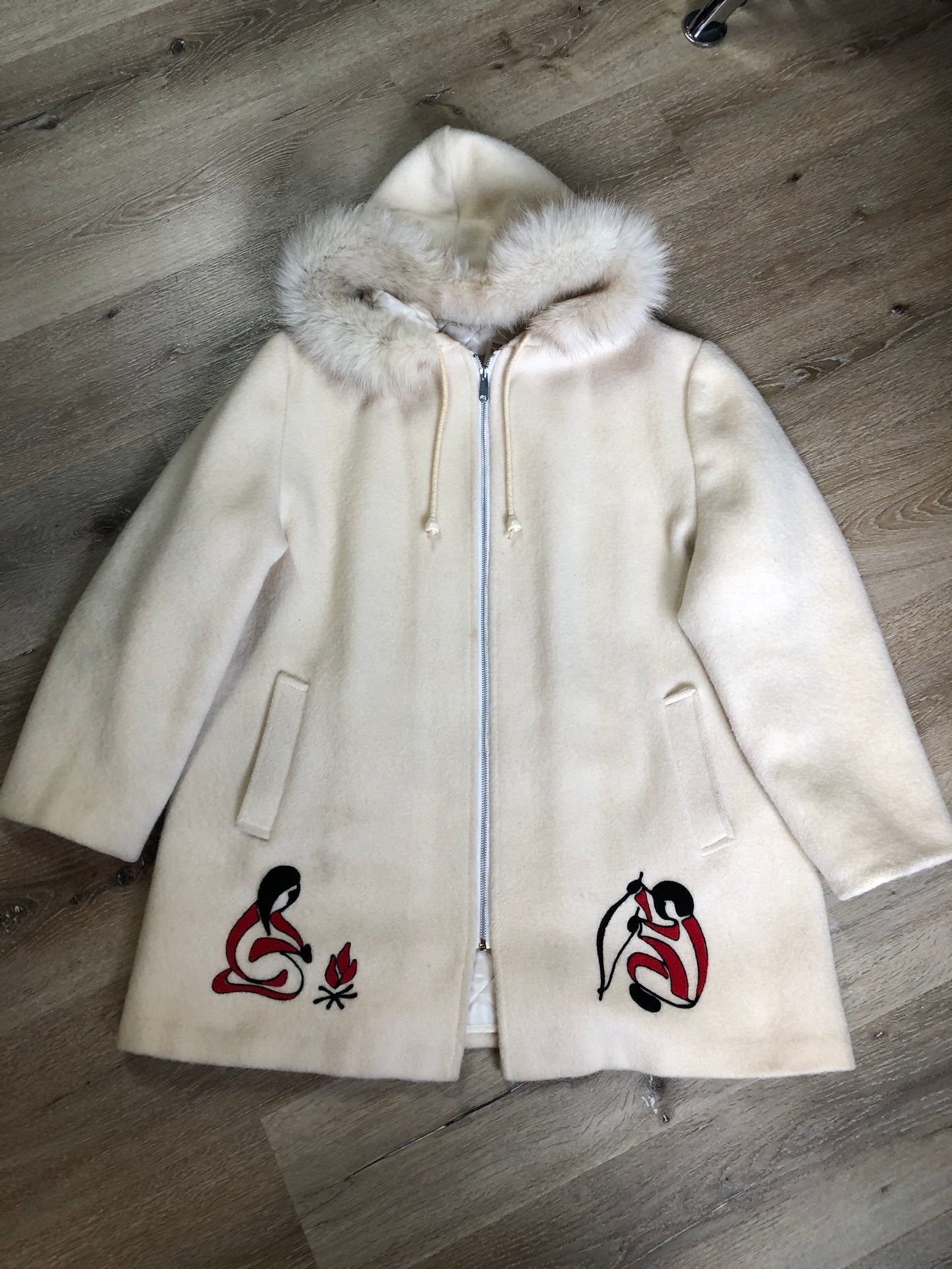 Kingspier Vintage - Canadian Sportswear pure virgin wool northern parka in cream. This parka features a hood with white fur trim, zipper closure, quilted lining, slash pockets, felt fire making design appliqués on the front and canoeing scene design on the back. Made in Canada.