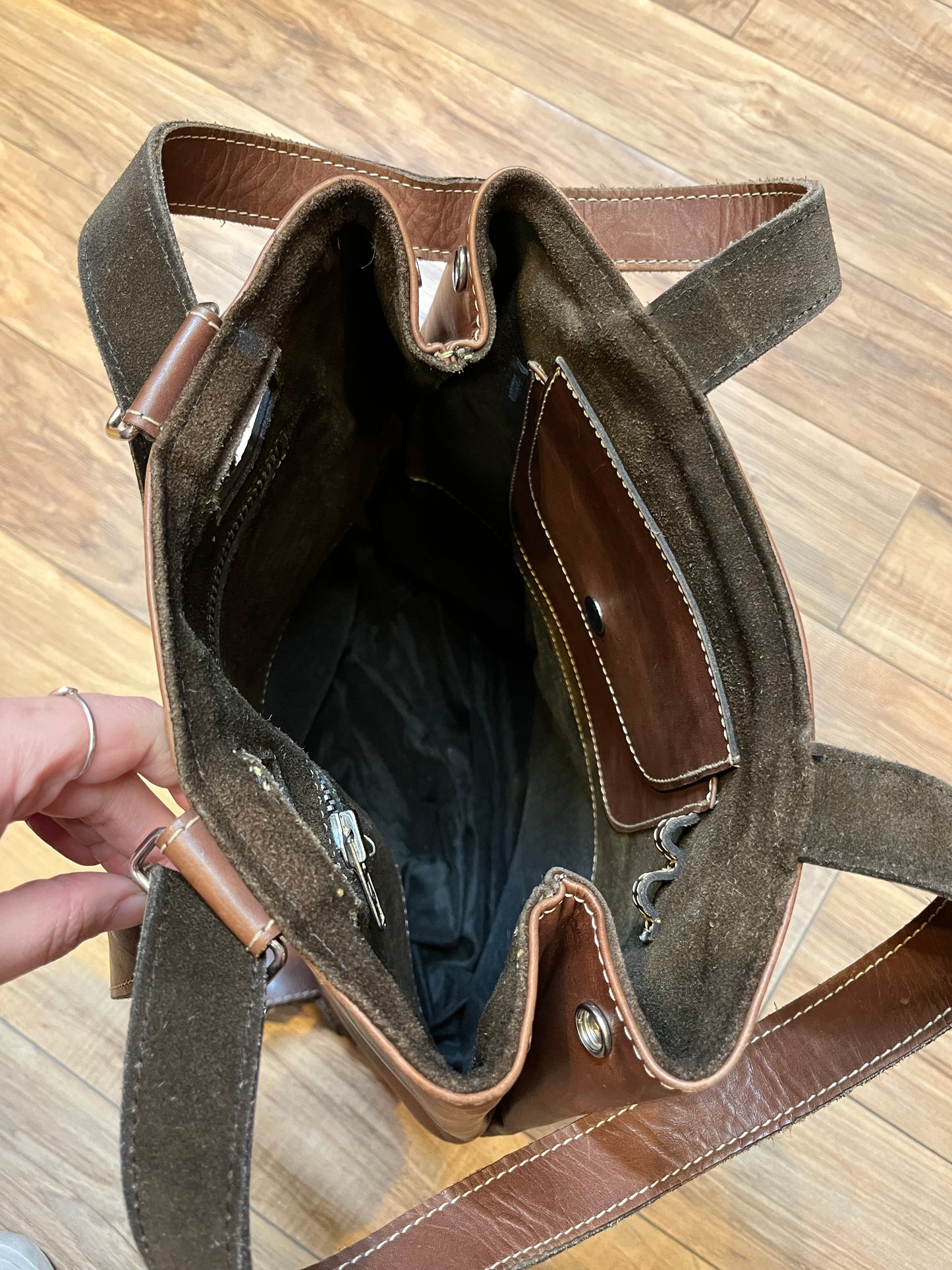 Tabique brown leather knapsack with suede lining, adjustable shoulder straps, two pockets and two pen holders inside the main compartment.