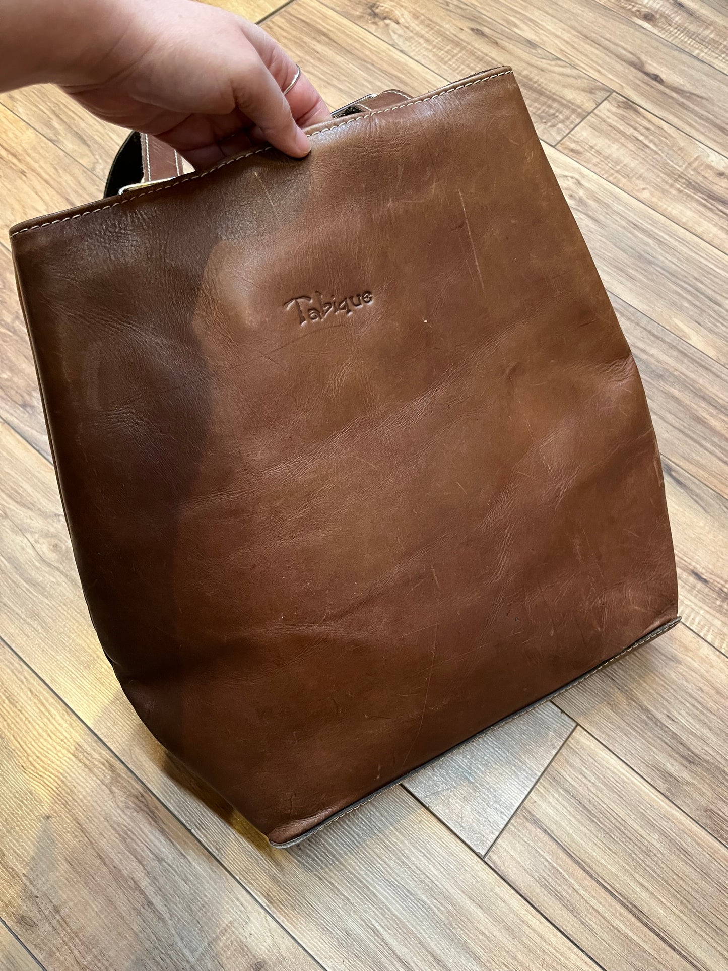 Tabique brown leather knapsack with suede lining, adjustable shoulder straps, two pockets and two pen holders inside the main compartment.
