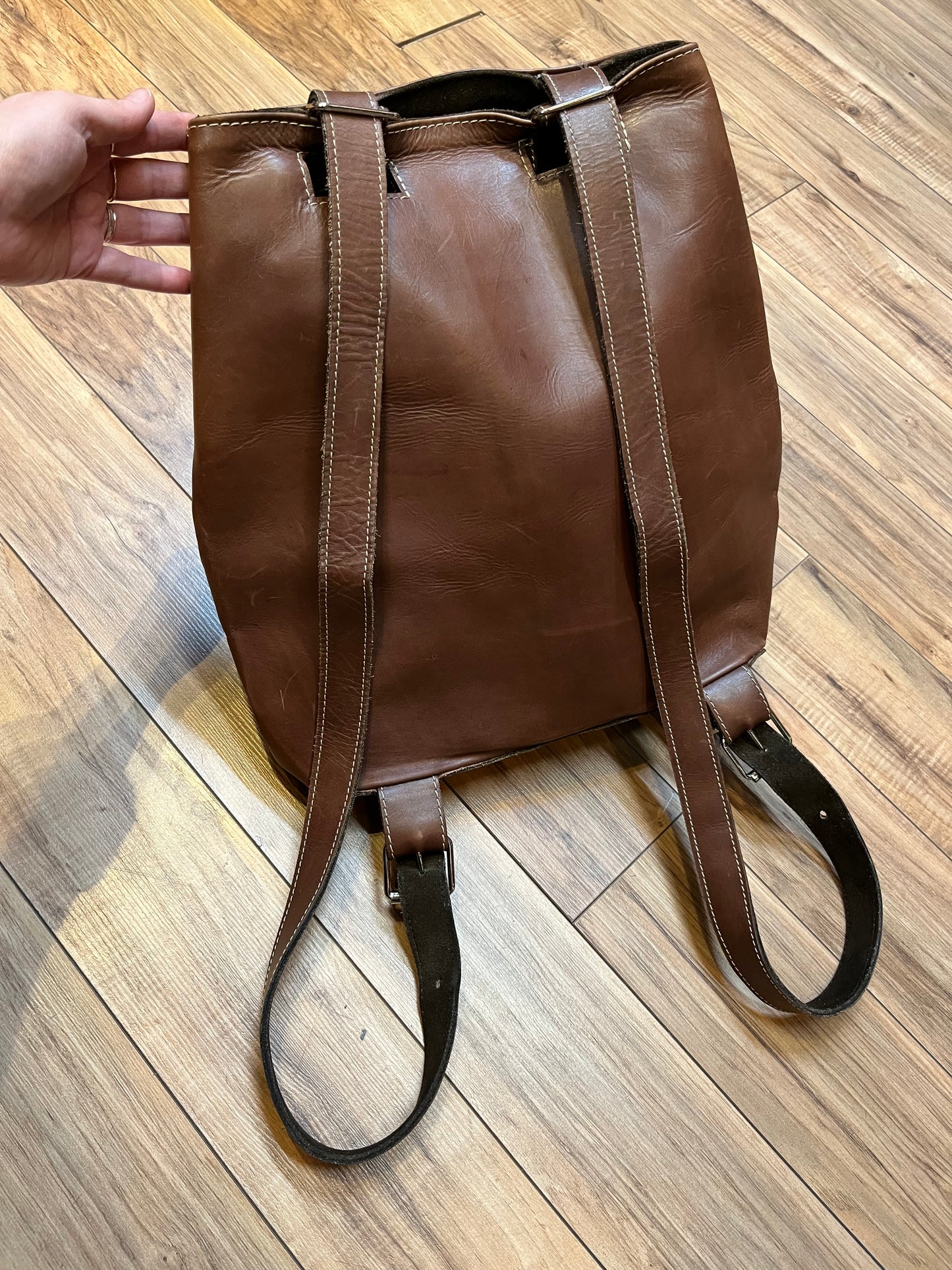 Tabique brown leather knapsack with suede lining, adjustable shoulder straps, two pockets and two pen holders inside the main compartment.