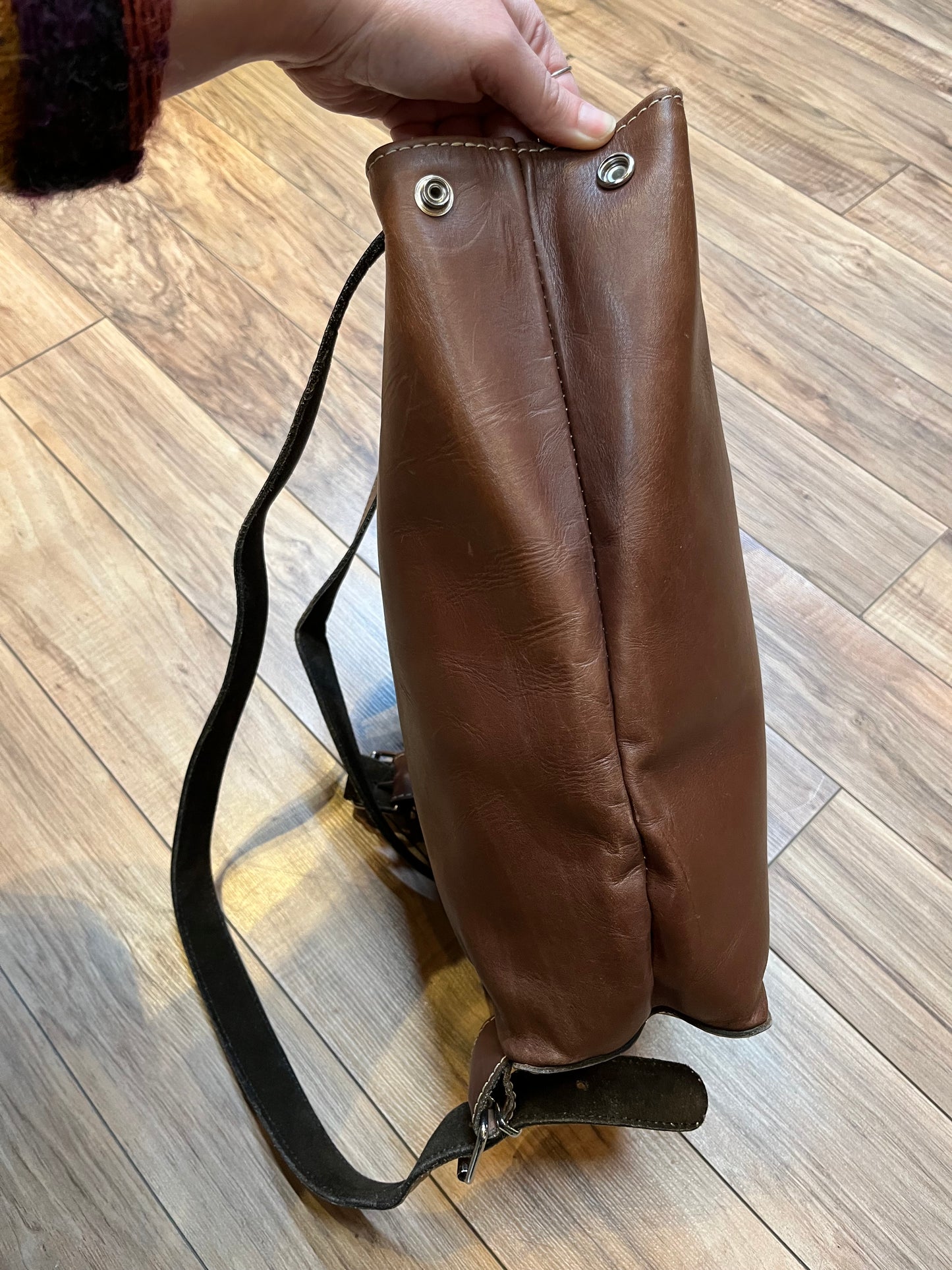 Tabique brown leather knapsack with suede lining, adjustable shoulder straps, two pockets and two pen holders inside the main compartment.