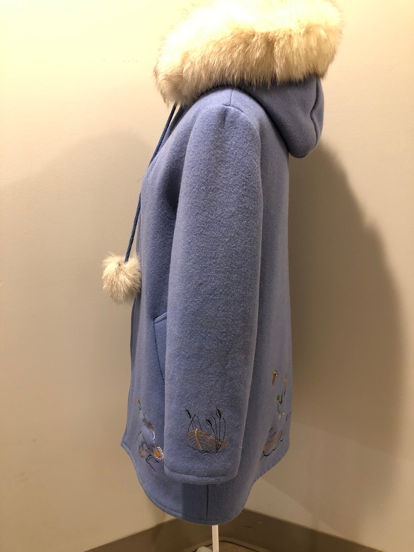 Kingspier Vintage - Northern Sun pure virgin wool northern style parka in light blue. This parka features a hood with white fur trim, zipper closure, quilted lining, slash pockets, hidden inside knit cuffs, embroidered geese design on the front and back and boats embroidered on the sleeves. Made in Canada.
