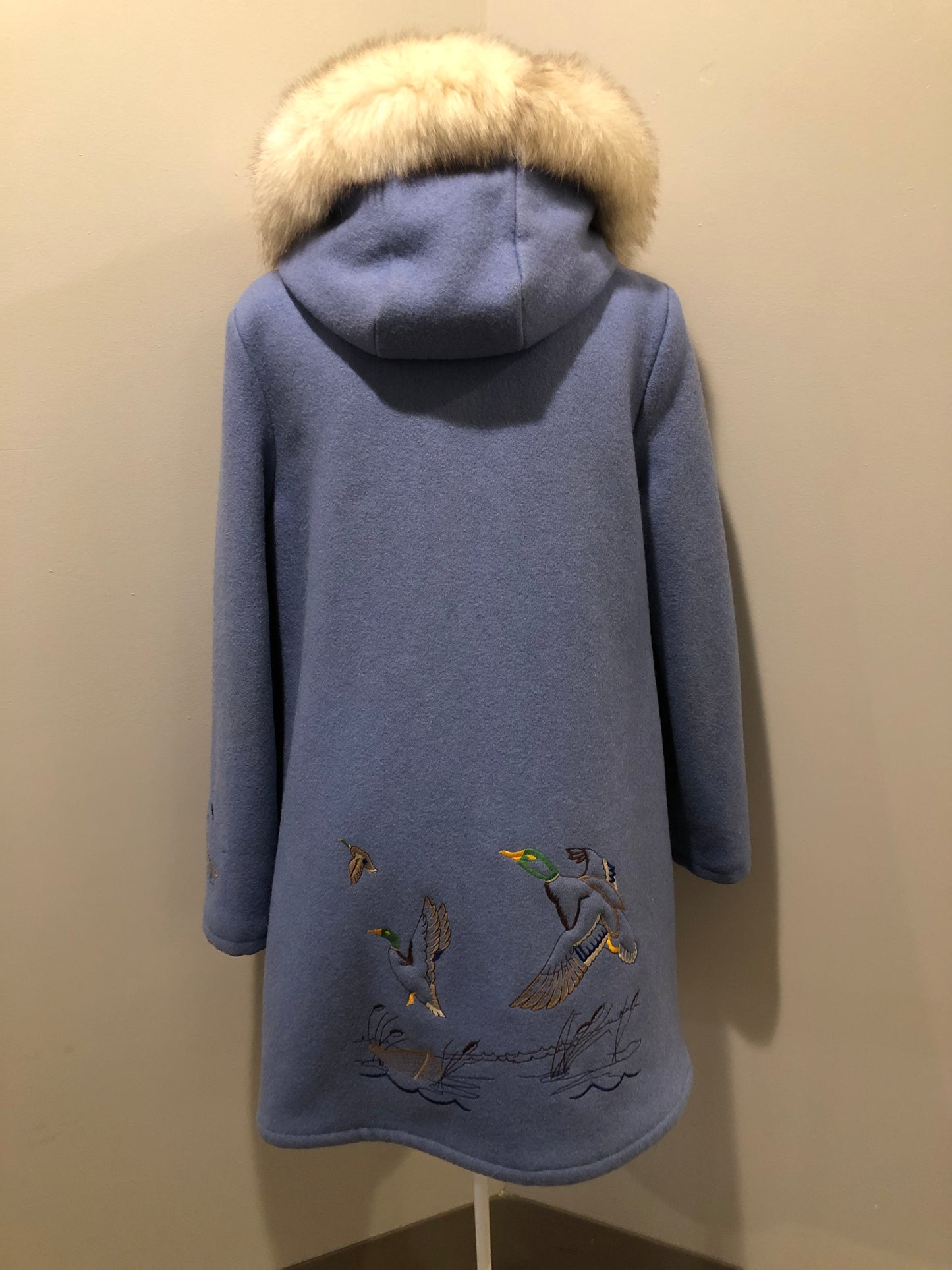 Kingspier Vintage - Northern Sun pure virgin wool northern style parka in light blue. This parka features a hood with white fur trim, zipper closure, quilted lining, slash pockets, hidden inside knit cuffs, embroidered geese design on the front and back and boats embroidered on the sleeves. Made in Canada.