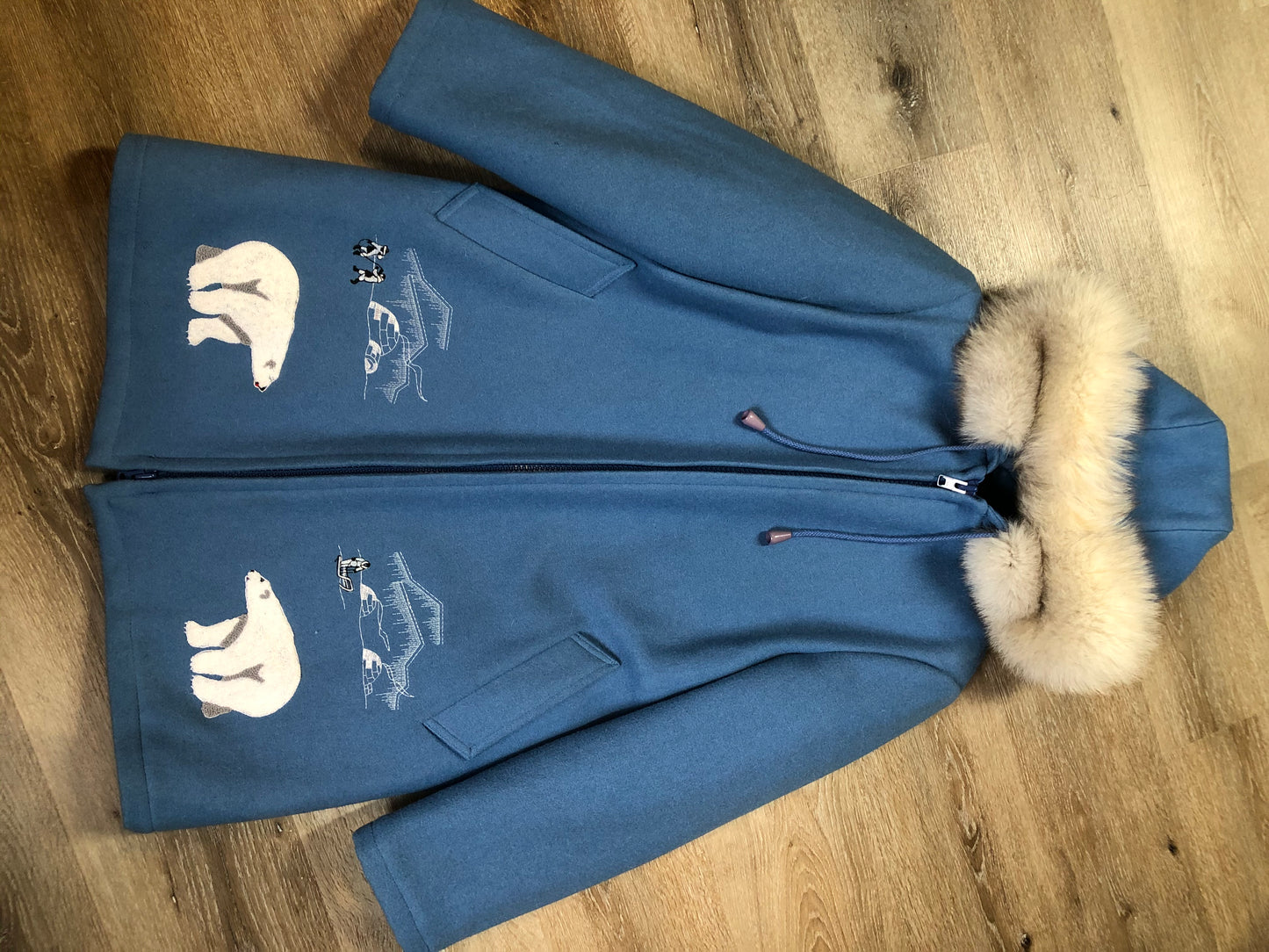 Kingspier Vintage - Northern Sun pure virgin wool northern parka in light blue. This parka features a hood with white fur trim, zipper closure, quilted lining, slash pockets, hidden inside knit cuffs, embroidered polar bear design on the front and back. Made in Canada.