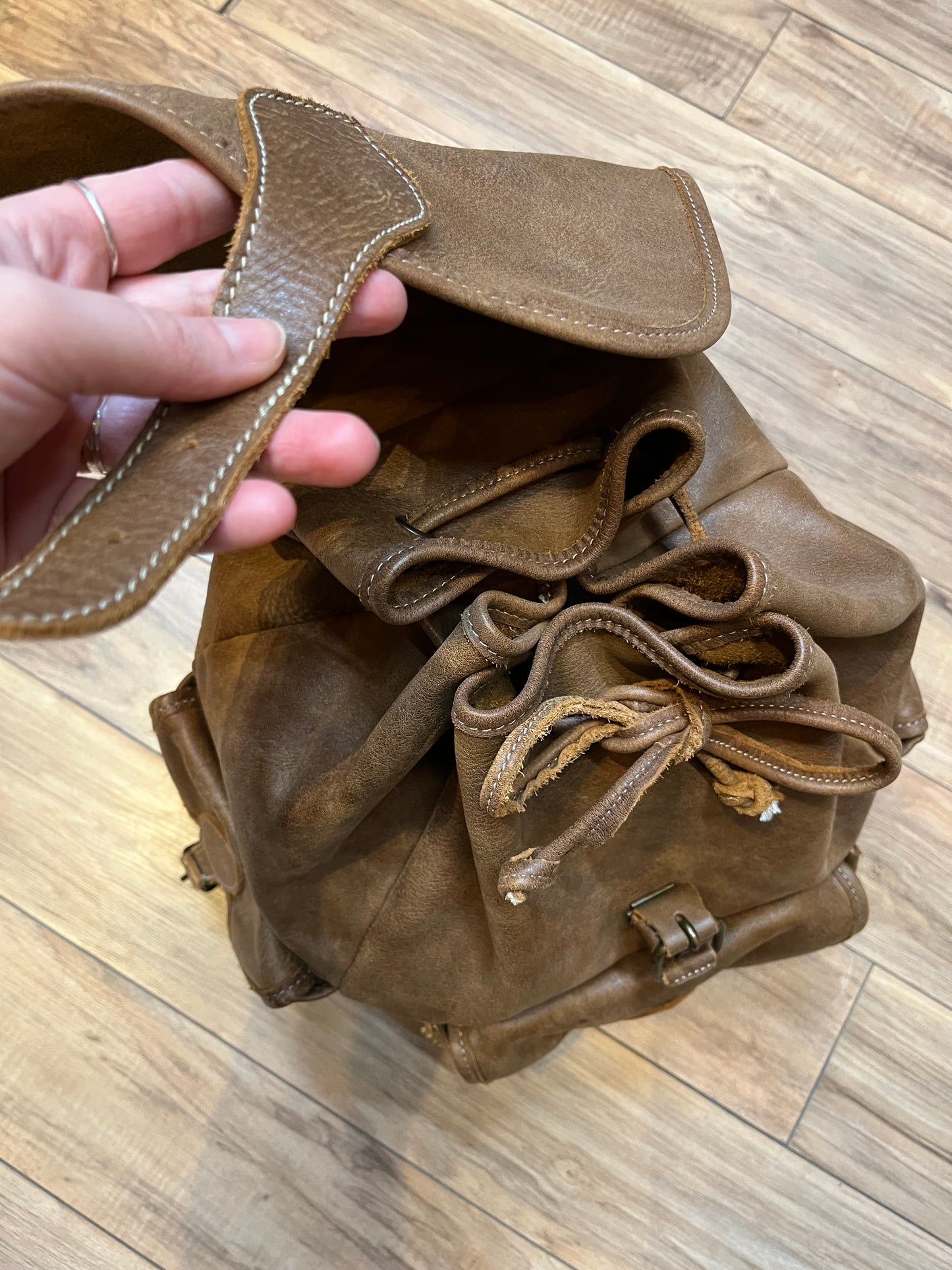 Vintage Roots Tribal Leather brown knapsack with adjustable shoulder straps, drawstring and buckle closures, one large main compartment and three small outer pockets.
Made in Canada
