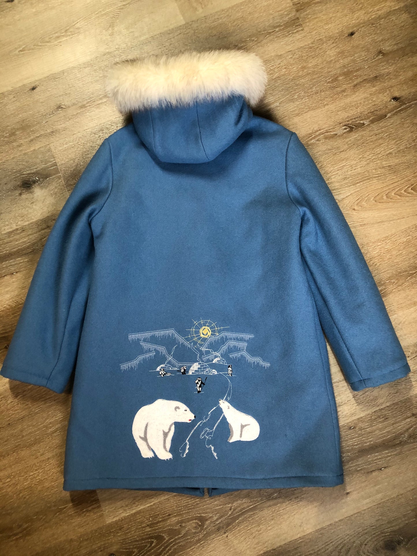 Kingspier Vintage - Northern Sun pure virgin wool northern parka in light blue. This parka features a hood with white fur trim, zipper closure, quilted lining, slash pockets, hidden inside knit cuffs, embroidered polar bear design on the front and back. Made in Canada.