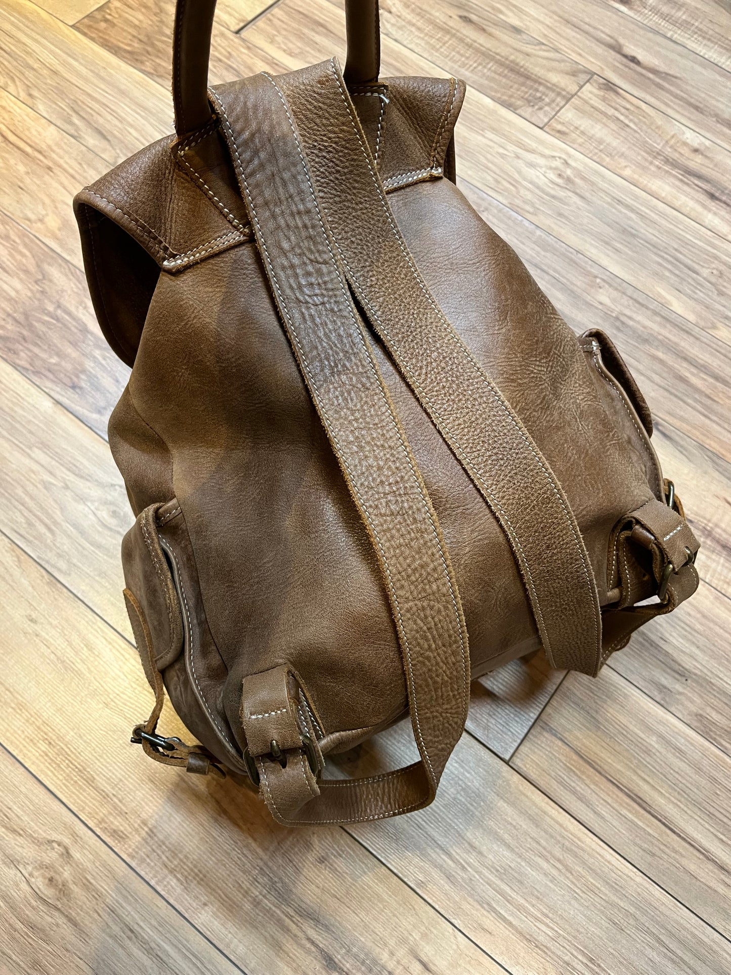Vintage Roots Tribal Leather brown knapsack with adjustable shoulder straps, drawstring and buckle closures, one large main compartment and three small outer pockets.
Made in Canada