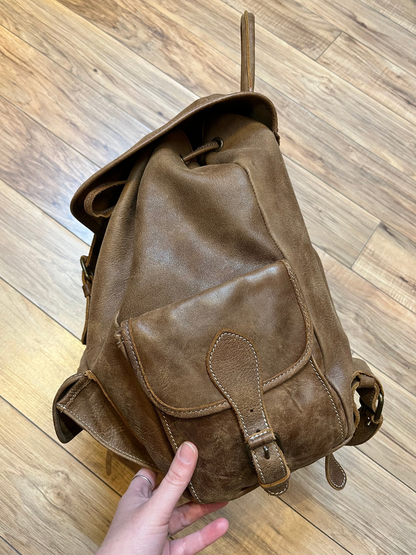 Vintage Roots Tribal Leather brown knapsack with adjustable shoulder straps, drawstring and buckle closures, one large main compartment and three small outer pockets.
Made in Canada