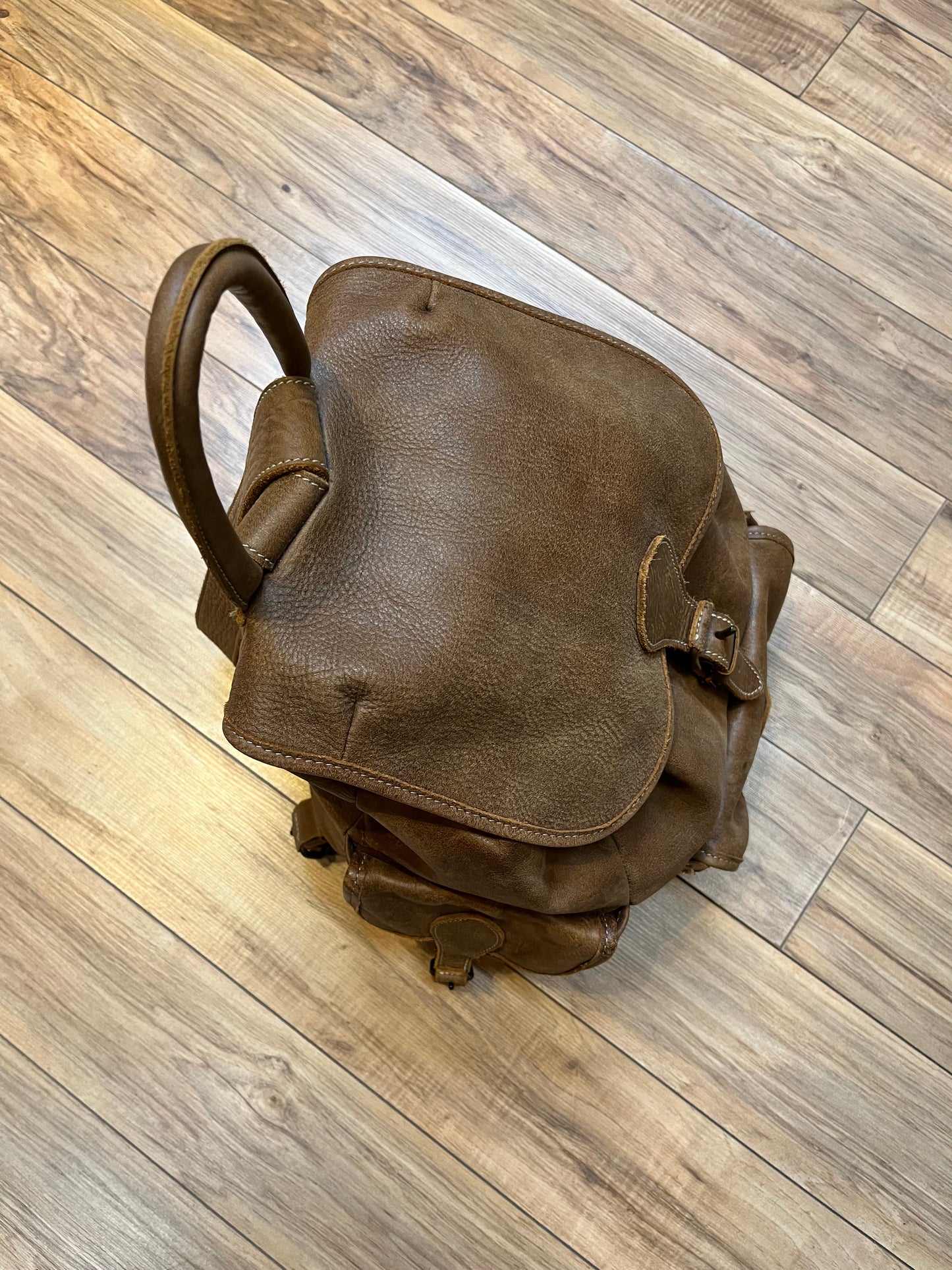 Vintage Roots Tribal Leather brown knapsack with adjustable shoulder straps, drawstring and buckle closures, one large main compartment and three small outer pockets.
Made in Canada