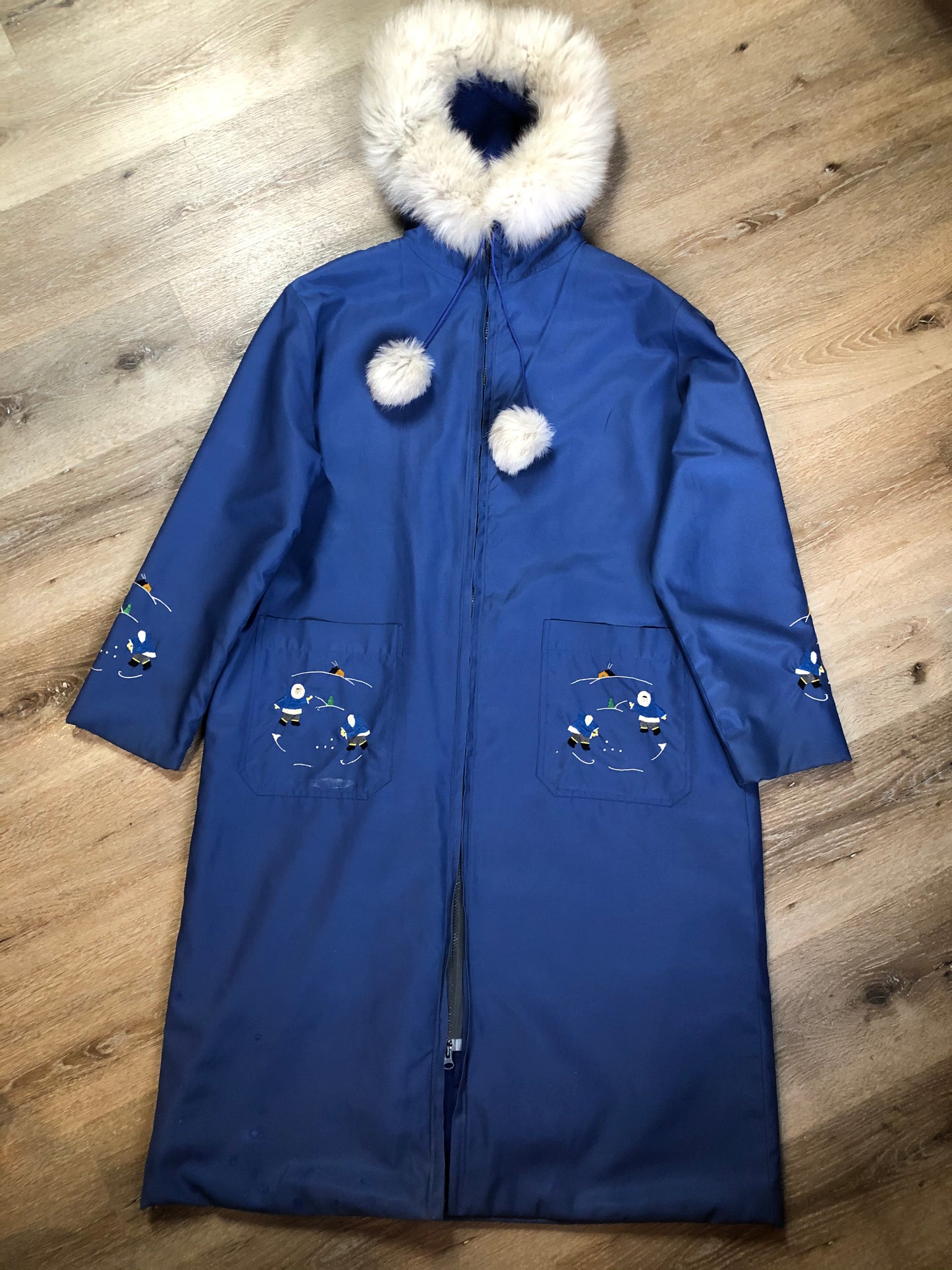 Kingspier Vintage - Blue northern parka made by Marilyn Bessey with wool blend lining, hood with white fur trim, fur Pom poms, zipper closure, patch pockets, arctic life design embroidered on the front pockets and the sleeves. Made in Canada.