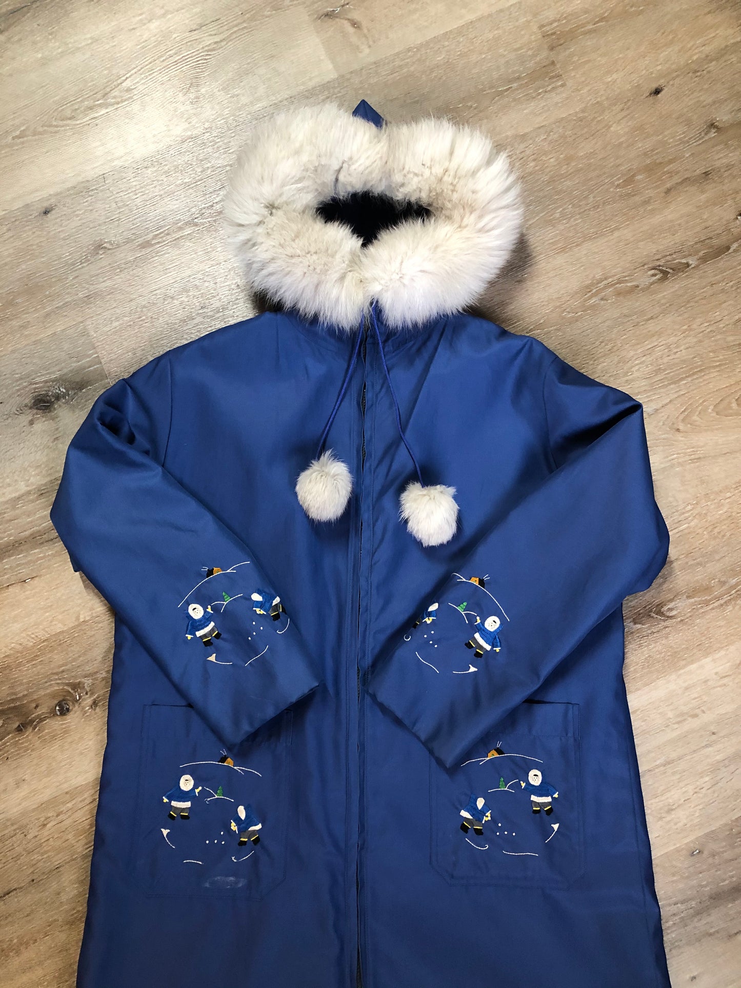 Kingspier Vintage - Blue northern parka made by Marilyn Bessey with wool blend lining, hood with white fur trim, fur Pom poms, zipper closure, patch pockets, arctic life design embroidered on the front pockets and the sleeves. Made in Canada.