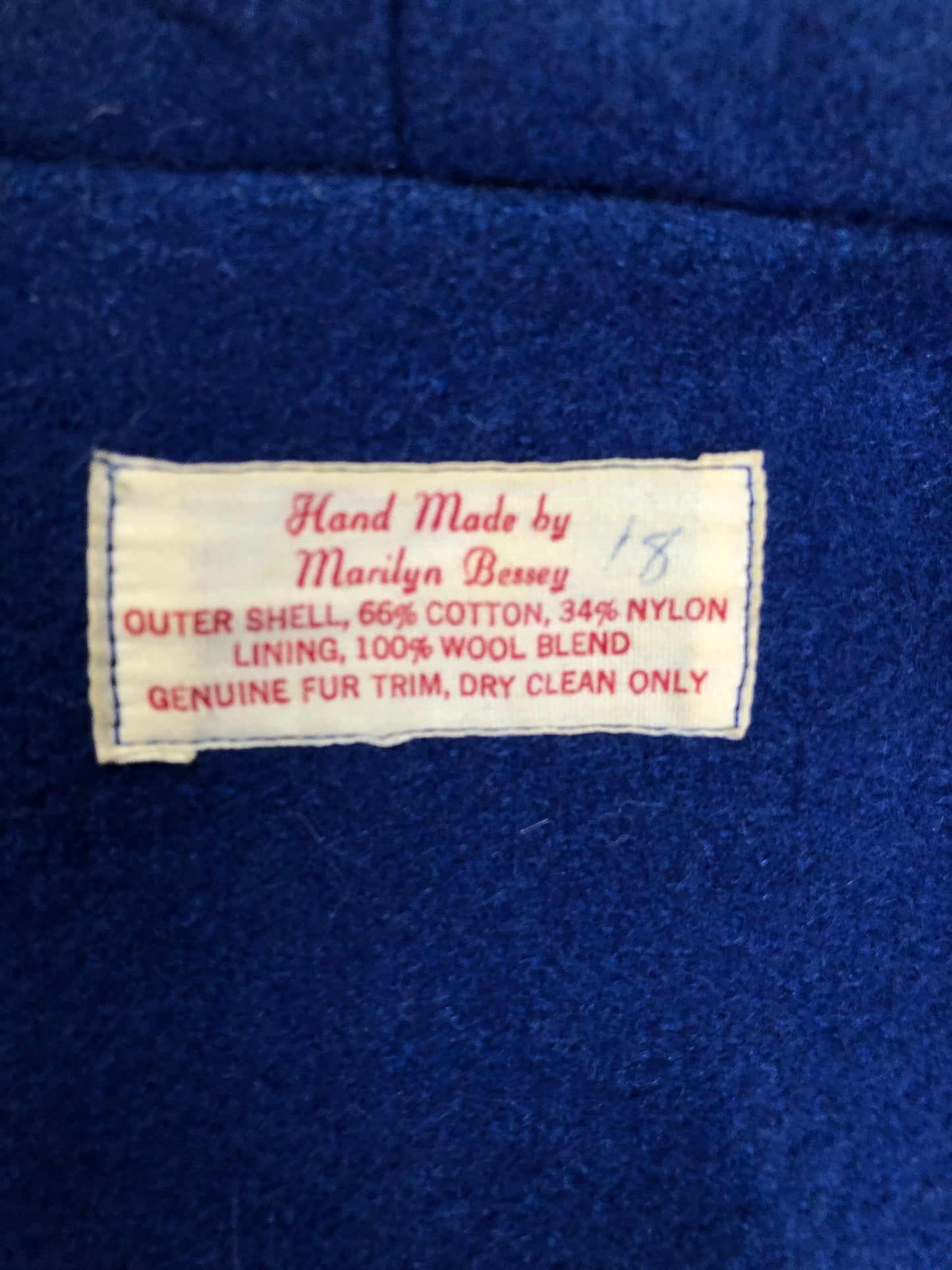 Kingspier Vintage - Blue northern parka made by Marilyn Bessey with wool blend lining, hood with white fur trim, fur Pom poms, zipper closure, patch pockets, arctic life design embroidered on the front pockets and the sleeves. Made in Canada.