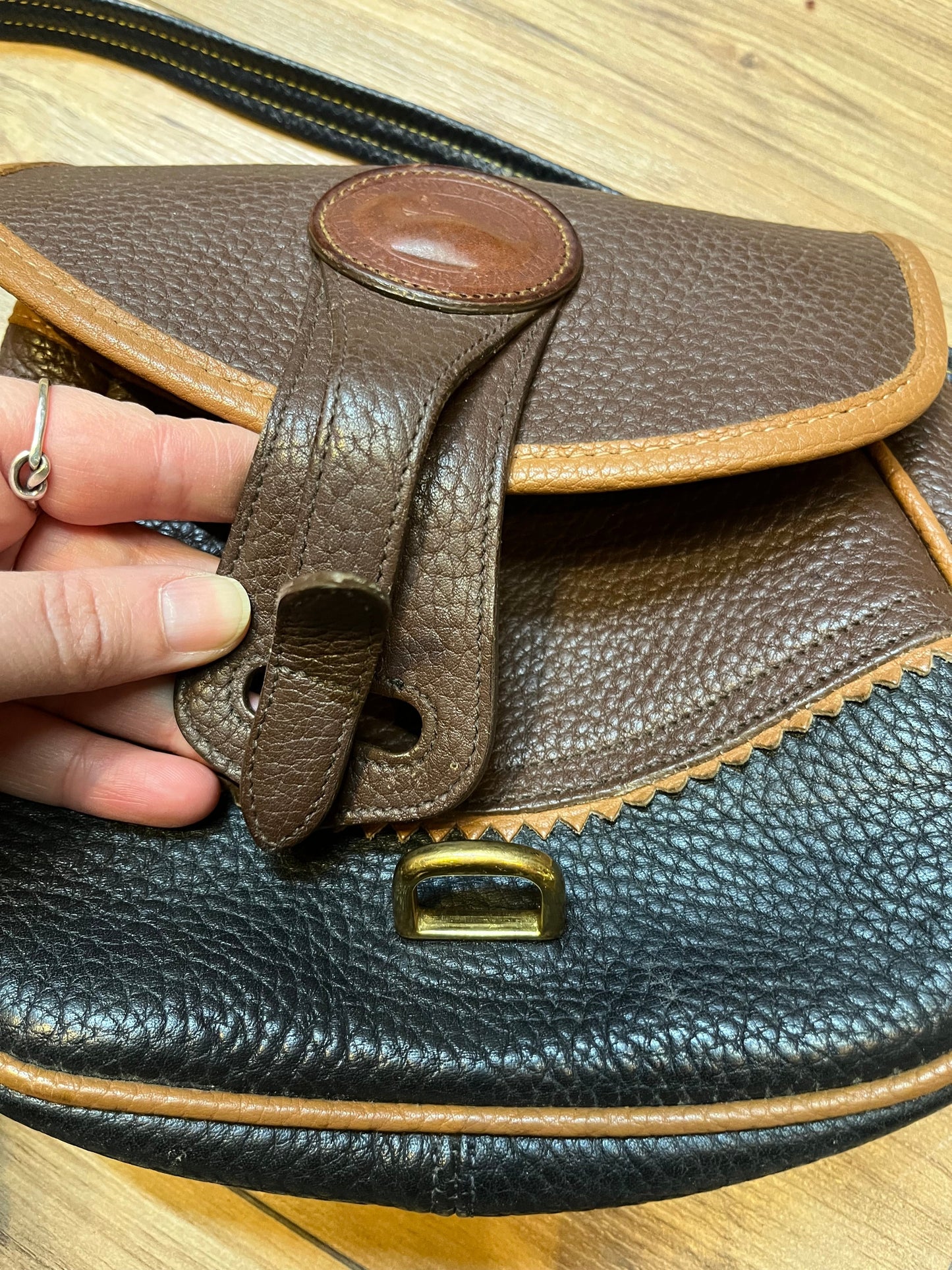 Dooney and Burke small navy and brown pebble leather crossbody bag with multiple pockets and brass hardware.