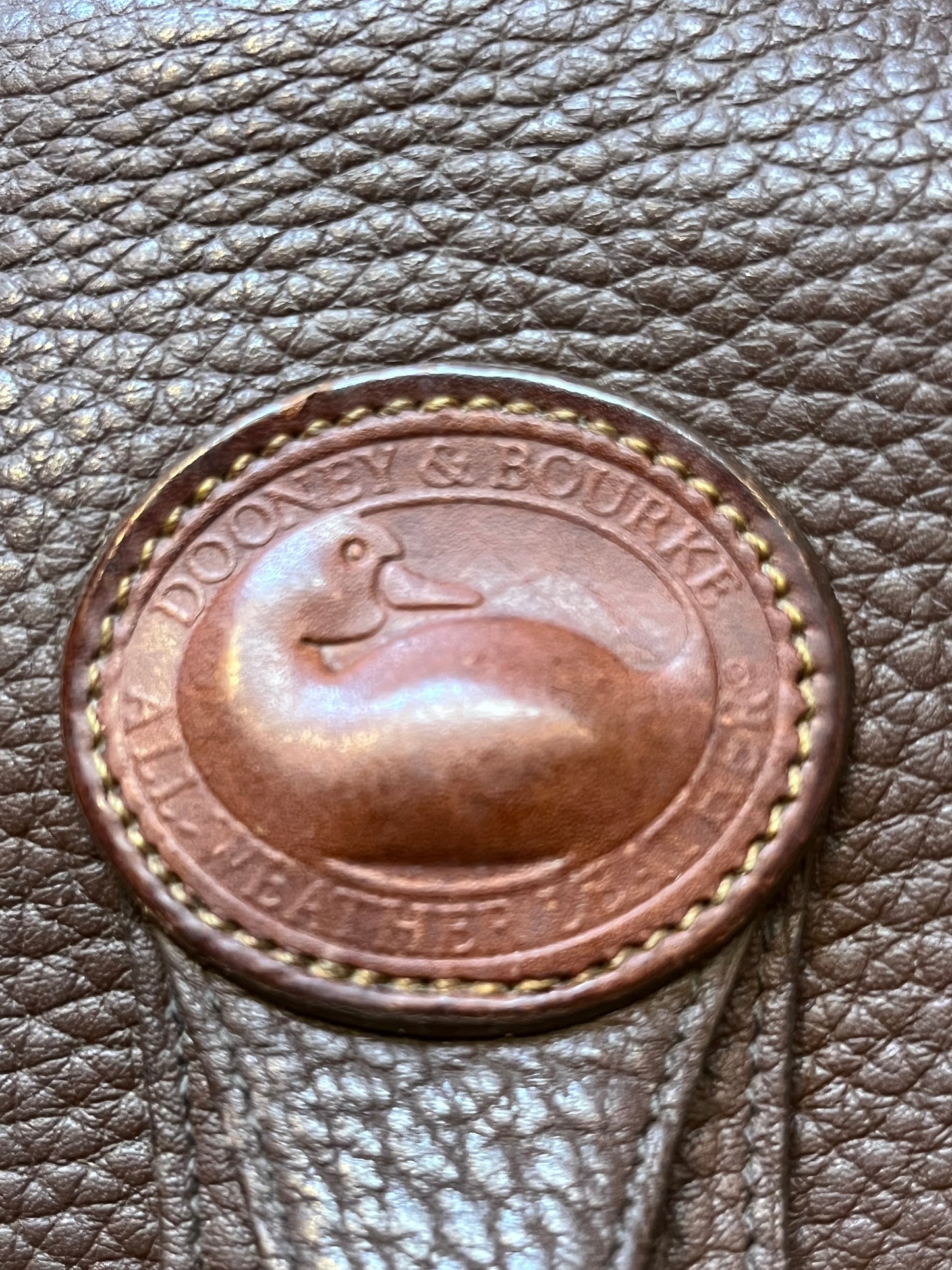 Dooney and Burke small navy and brown pebble leather crossbody bag with multiple pockets and brass hardware.