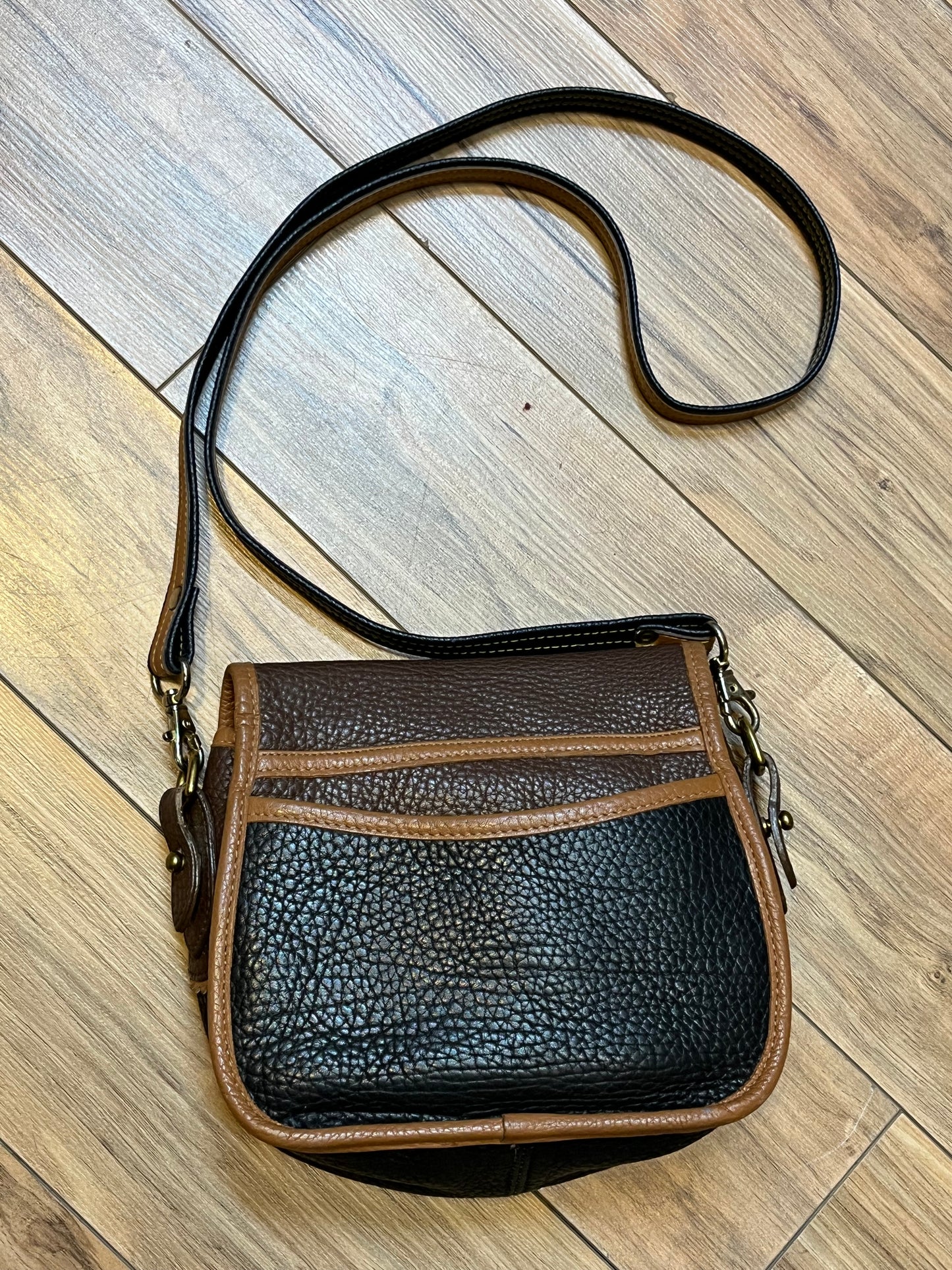 Dooney and Burke small navy and brown pebble leather crossbody bag with multiple pockets and brass hardware.