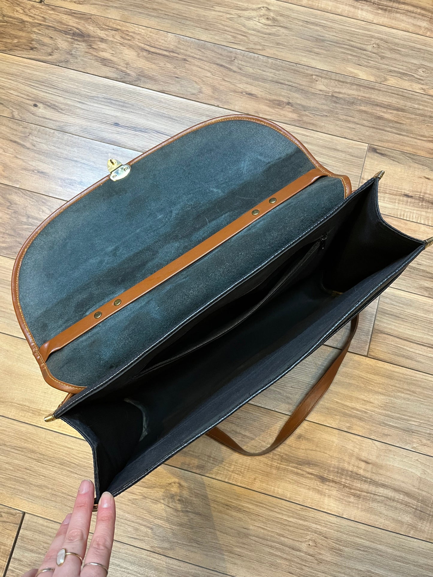 Dooney and Burke all weather leather briefcase in navy with top handle, shoulder strap and brass hardware.