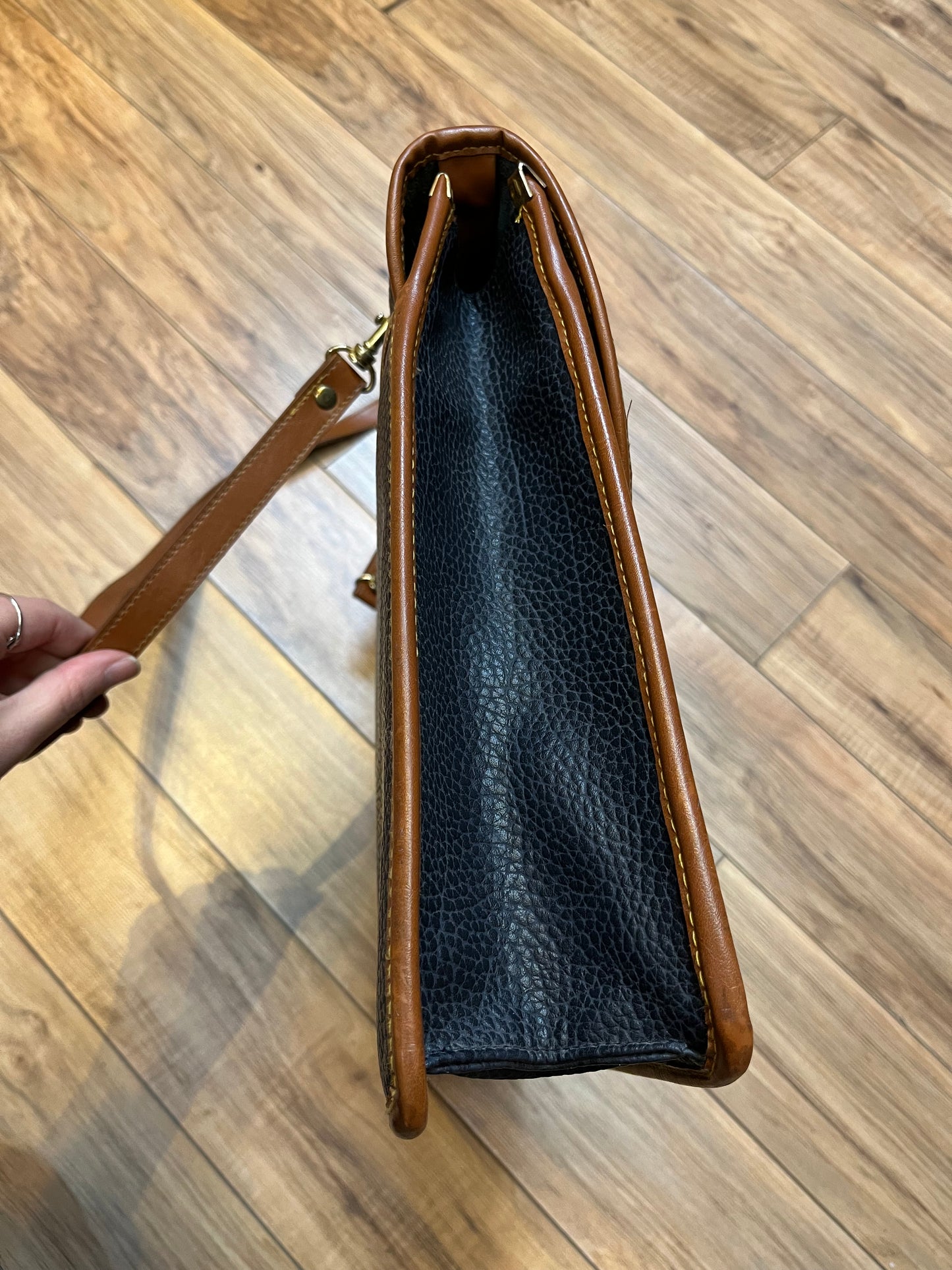 Dooney and Burke all weather leather briefcase in navy with top handle, shoulder strap and brass hardware.