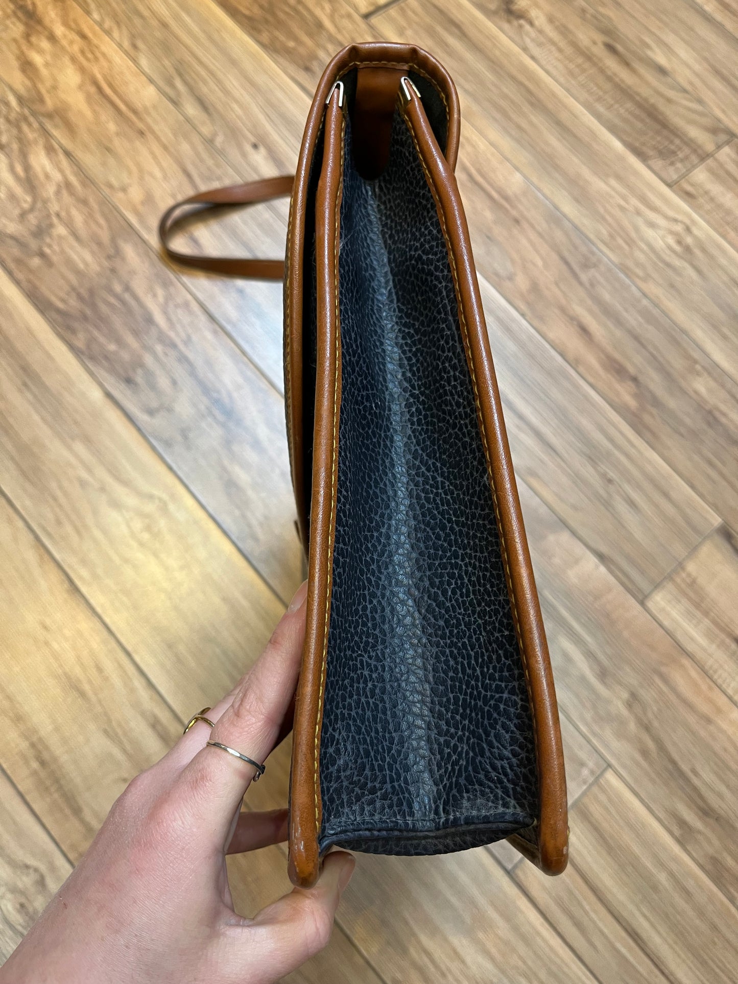 Dooney and Burke all weather leather briefcase in navy with top handle, shoulder strap and brass hardware.