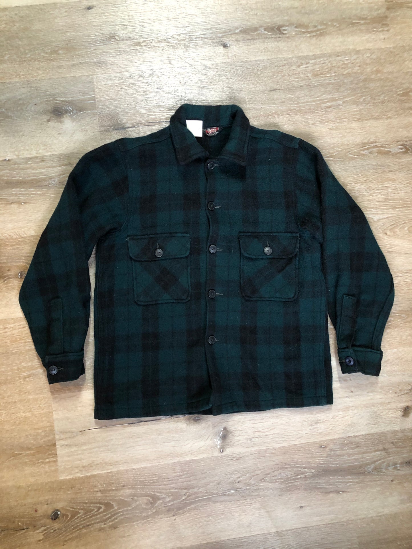 Kingspier Vintage - Woolrich dark green plaid wool lumberjack shirt with button closures and two flap pockets on the chest.