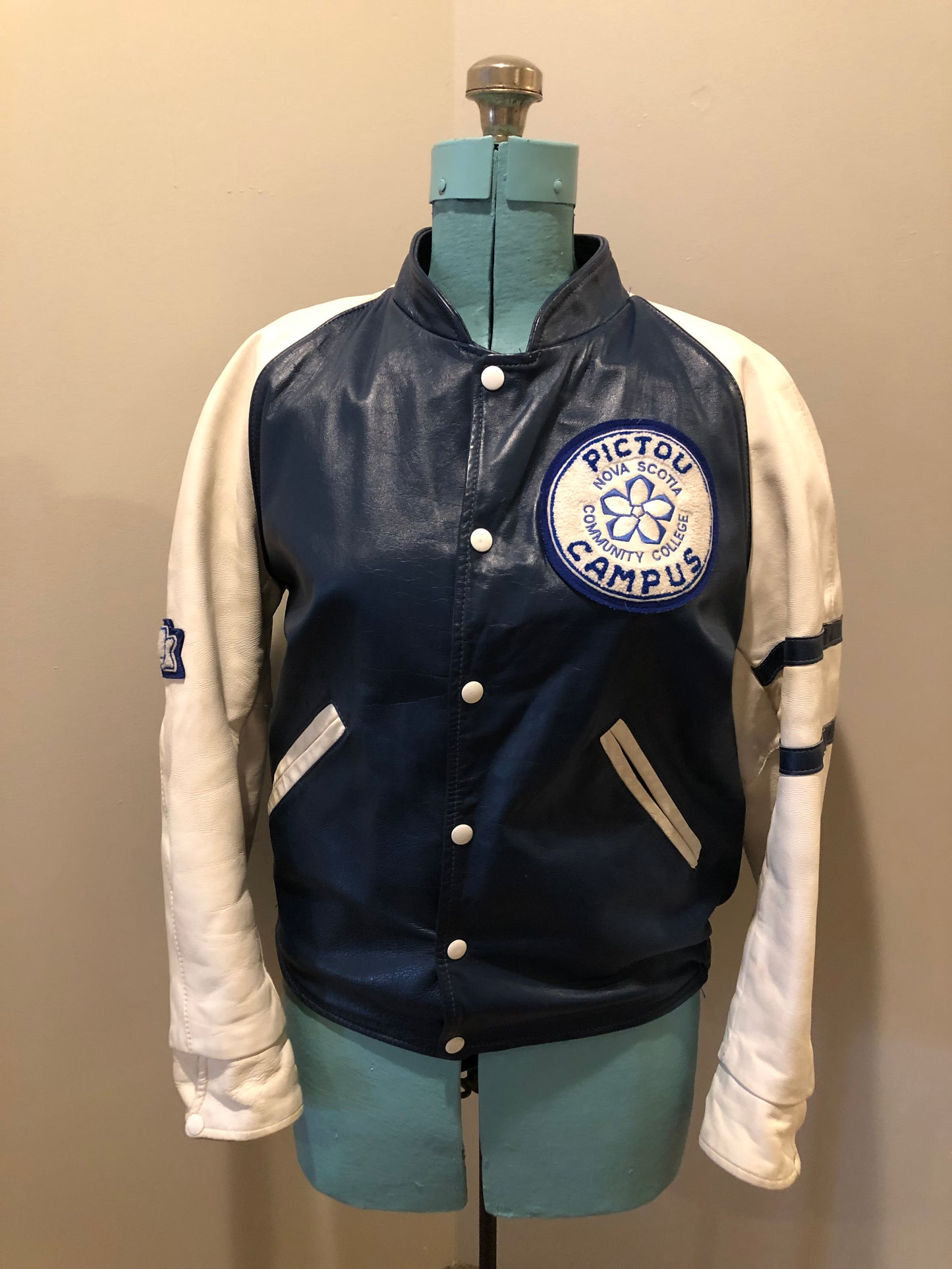 Kingspier Vintage - Vintage NSCC Pictou Campus leather varsity jacket in blue and white with snap closures, slash pockets, “Pictou Campus” embroidered on the chest, “NSCC” Embroidered on the back and “Ron” monogram embroidered on the sleeve,