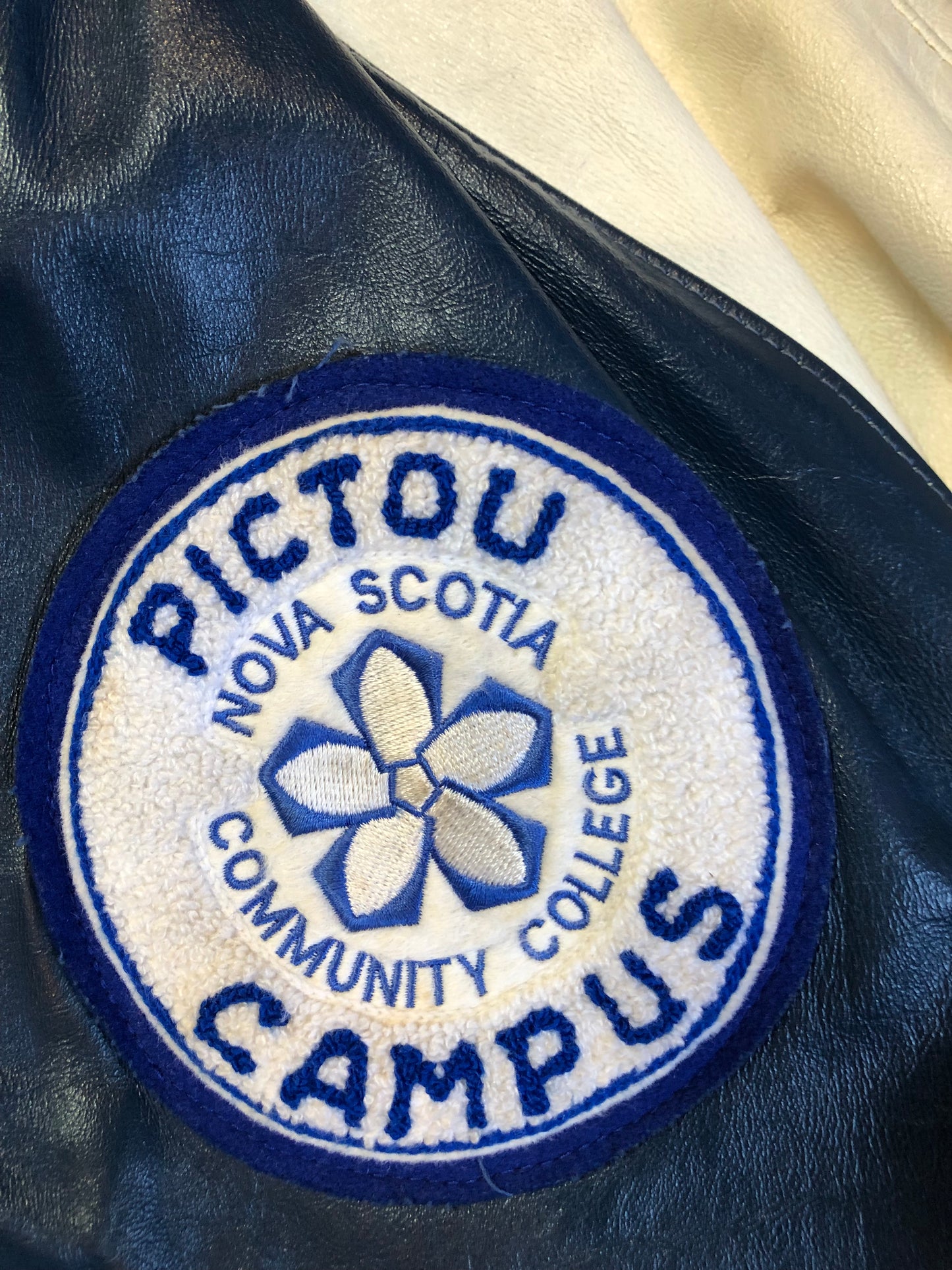 Kingspier Vintage - Vintage NSCC Pictou Campus leather varsity jacket in blue and white with snap closures, slash pockets, “Pictou Campus” embroidered on the chest, “NSCC” Embroidered on the back and “Ron” monogram embroidered on the sleeve,