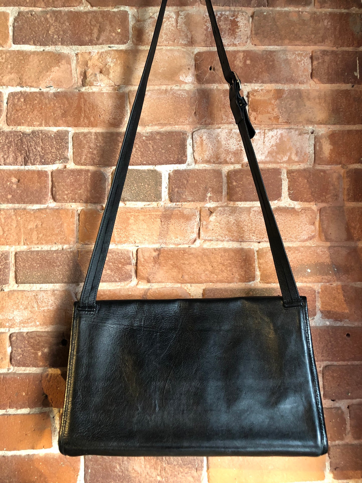 Kingspier Vintage - Black leather satchel with ornate front closure, lined in maroon coloured leather and features many inside pockets.