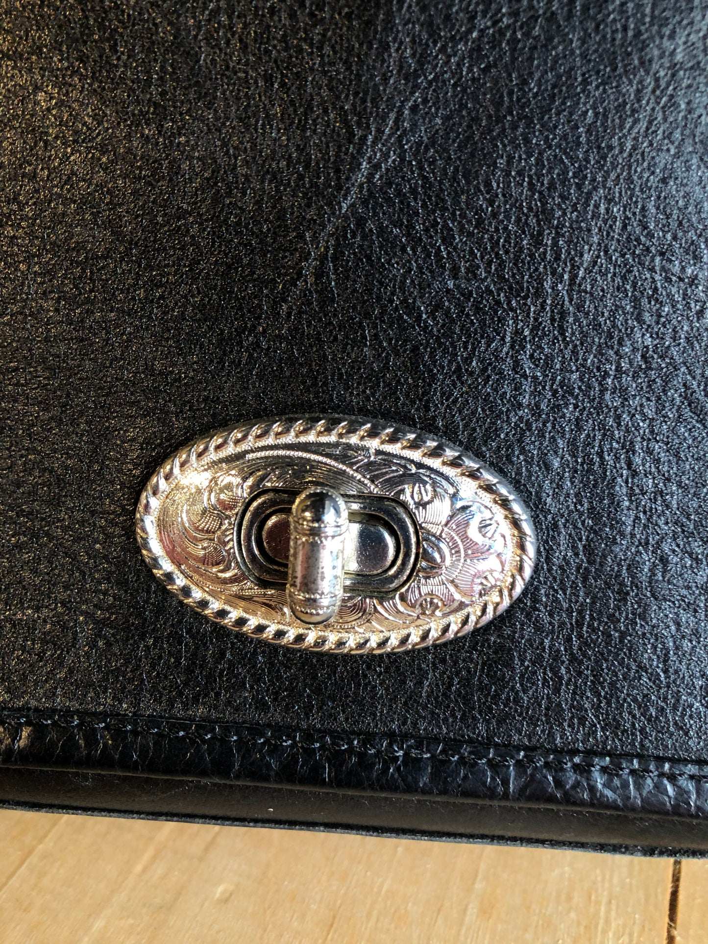 Kingspier Vintage - Black leather satchel with ornate front closure, lined in maroon coloured leather and features many inside pockets.