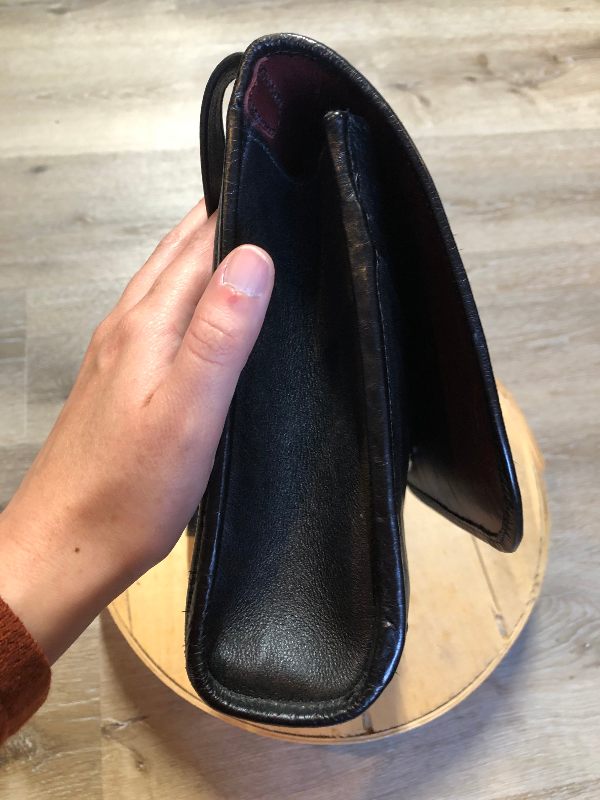 Kingspier Vintage - Black leather satchel with ornate front closure, lined in maroon coloured leather and features many inside pockets.