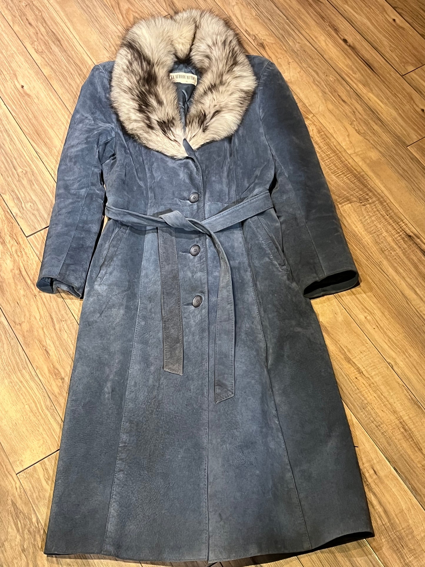 Vintage Leather Attic long blue/grey suede coat with white fur collar, belt, two front pockets, button closures and a quilted lining.
Made in Canada, Size 13/14