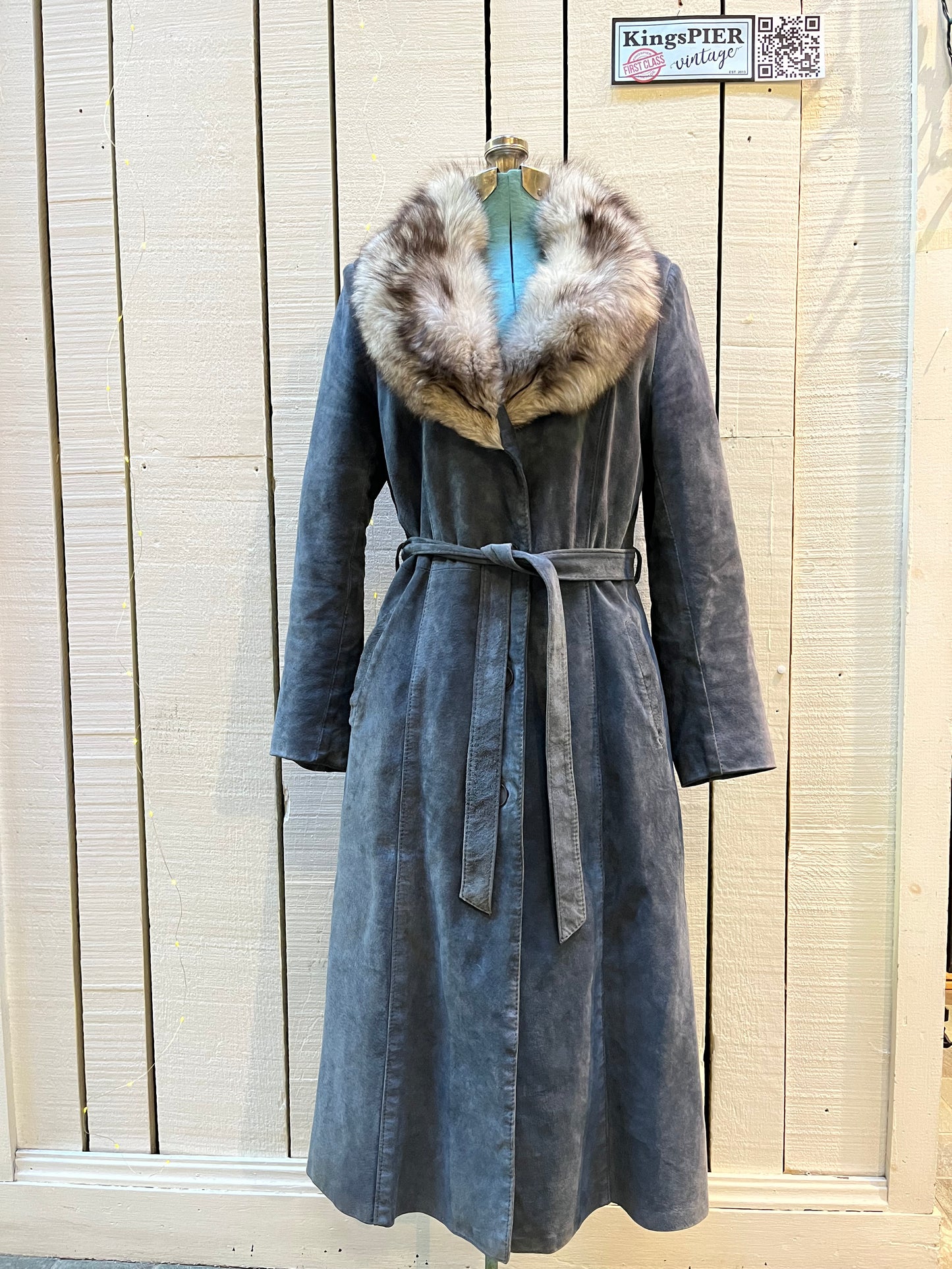 Vintage Leather Attic long blue/grey suede coat with white fur collar, belt, two front pockets, button closures and a quilted lining.
Made in Canada, Size 13/14