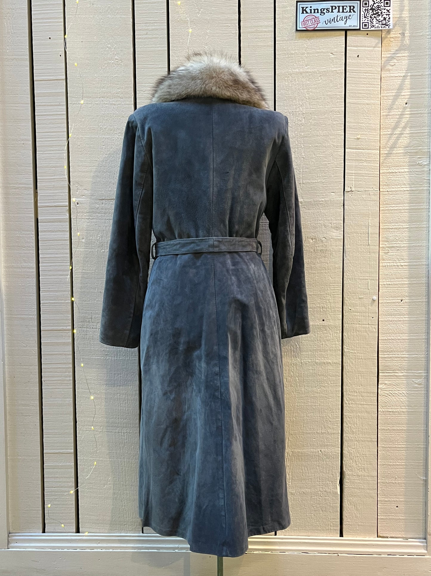 Vintage Leather Attic long blue/grey suede coat with white fur collar, belt, two front pockets, button closures and a quilted lining.
Made in Canada, Size 13/14