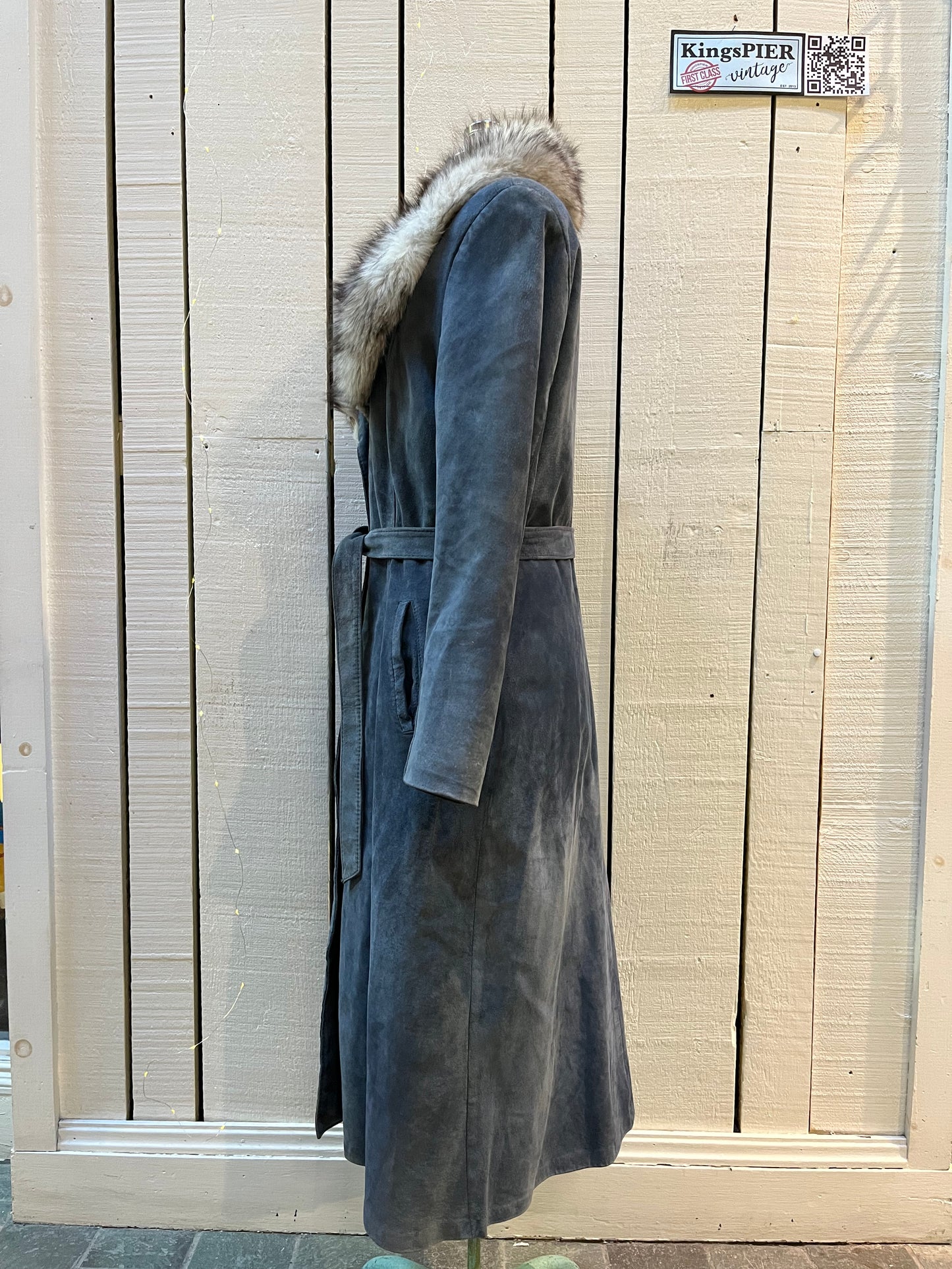 Vintage Leather Attic long blue/grey suede coat with white fur collar, belt, two front pockets, button closures and a quilted lining.
Made in Canada, Size 13/14