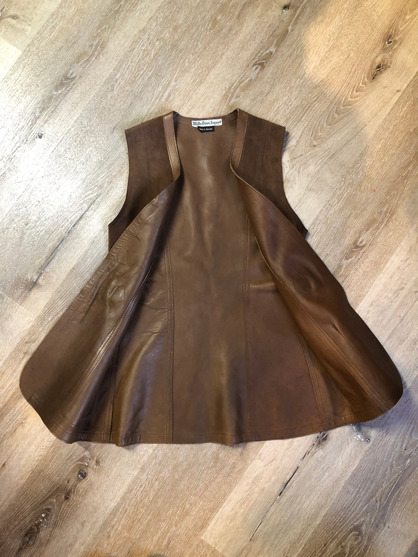 Vintage Mills Brothers deadstock 1960’s brown suede vest with large gold geometric front clasp, leather lining and trim and two patch pockets in the front. Suede and leather are buttery soft. Made in England - Kingspier Vintage