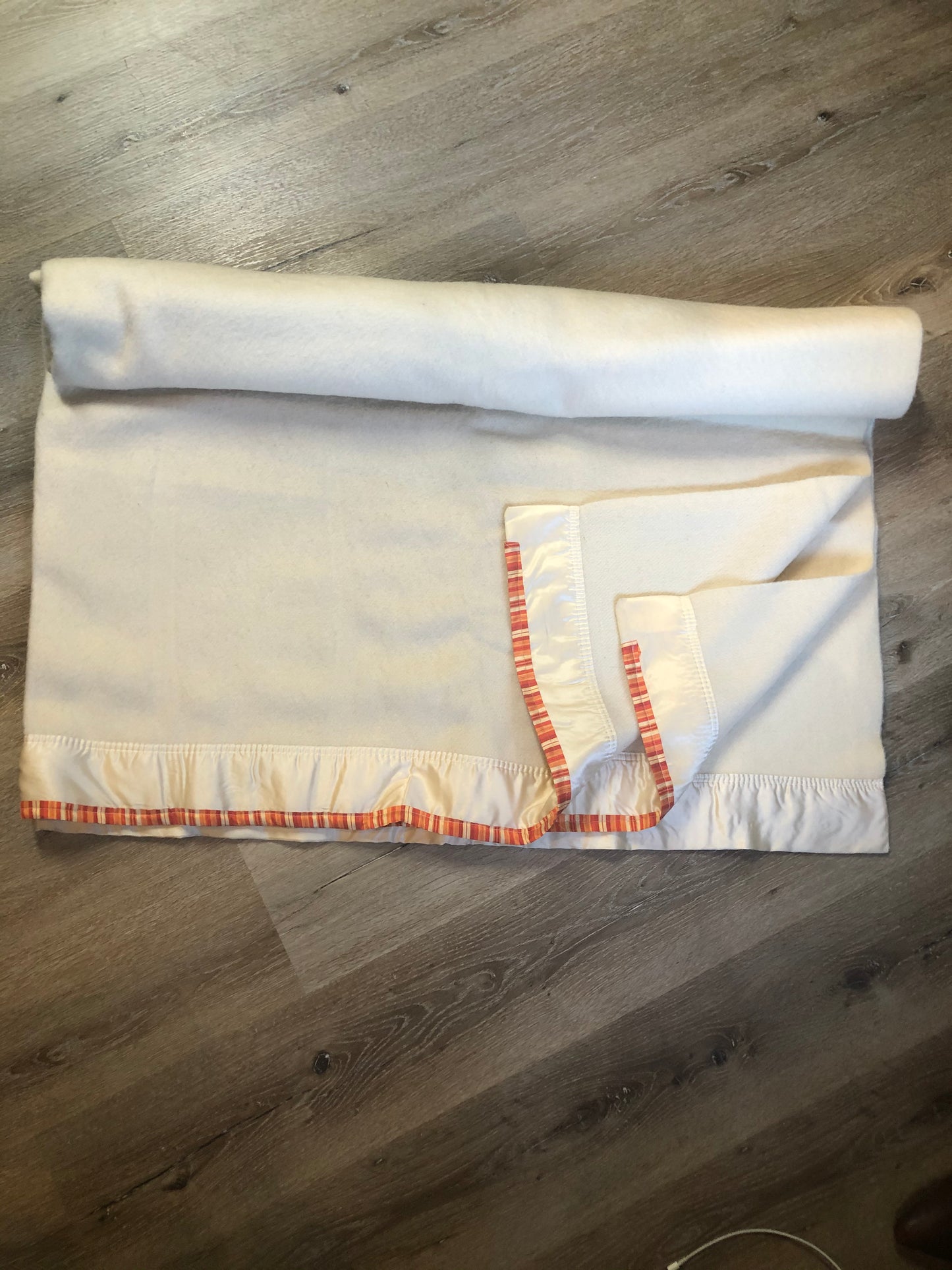 Kingspier Vintage - White 100% wool blanket with white ribbon trim on one end and a red, yellow and orange striped ribbon on the other end.
Fits a double bed.