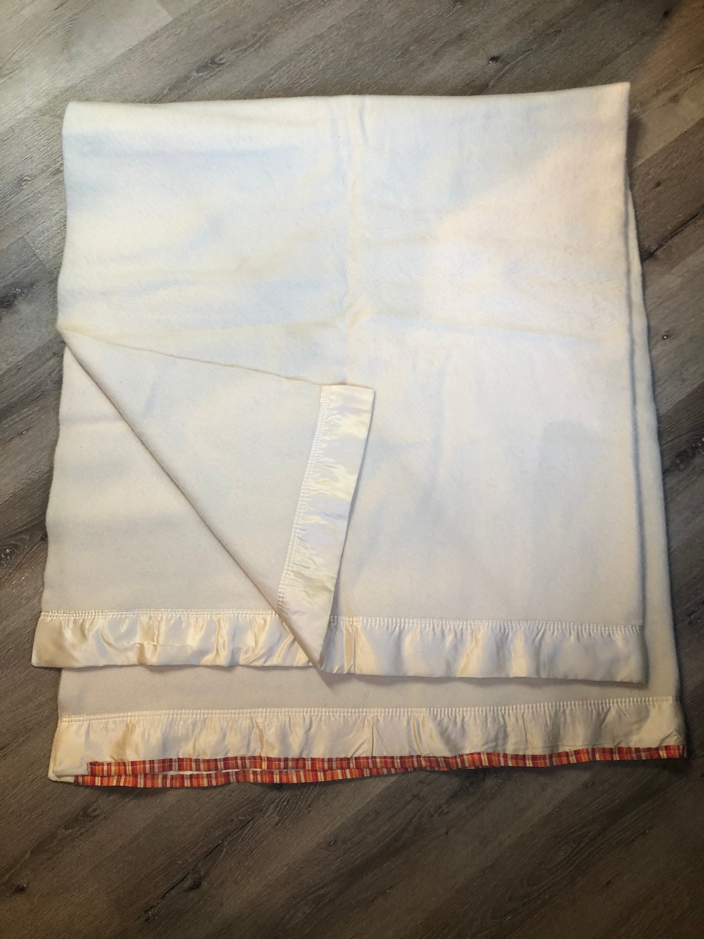 Kingspier Vintage - White 100% wool blanket with white ribbon trim on one end and a red, yellow and orange striped ribbon on the other end.
Fits a double bed.
