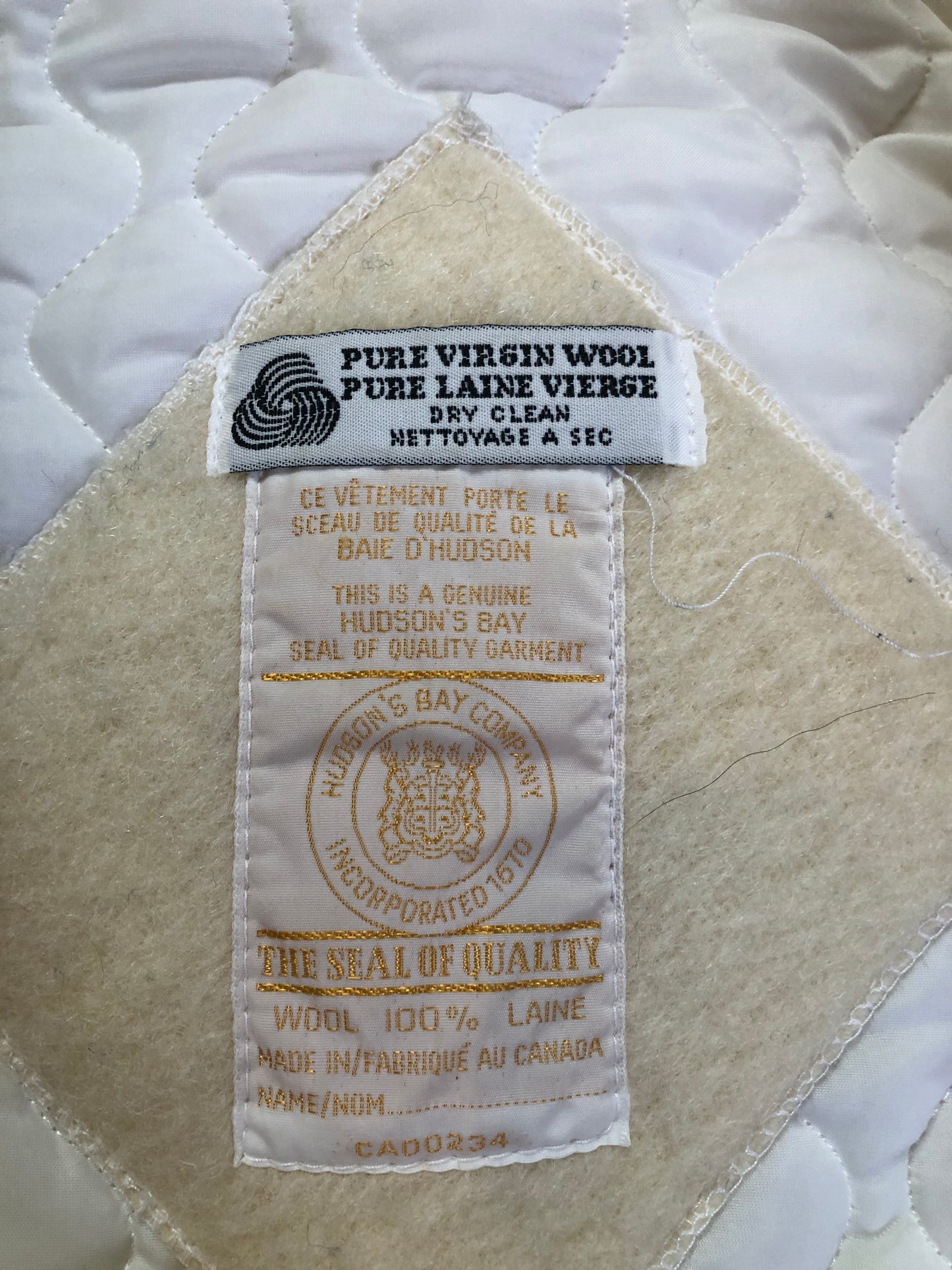 Kingspier Vintage - Hudson’s Bay Company white pure virgin wool northern parka featuring a hood with fox fur trim, zipper closure, quilted lining, inside drawstring, slash pockets, hidden knit cuffs and tree a nd igloo design suede appliqué on the front and back. Made in Canada. Size 14/ large.