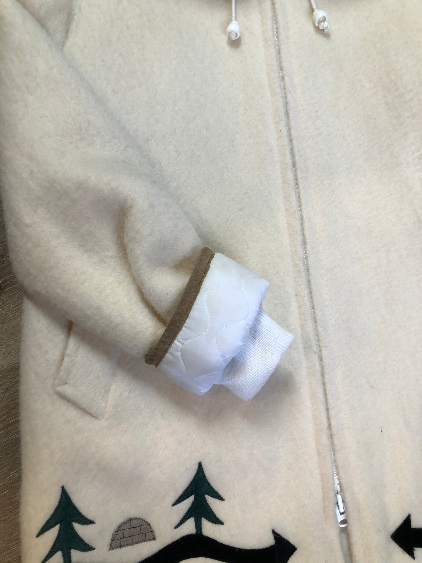 Kingspier Vintage - Hudson’s Bay Company white pure virgin wool northern parka featuring a hood with fox fur trim, zipper closure, quilted lining, inside drawstring, slash pockets, hidden knit cuffs and tree a nd igloo design suede appliqué on the front and back. Made in Canada. Size 14/ large.