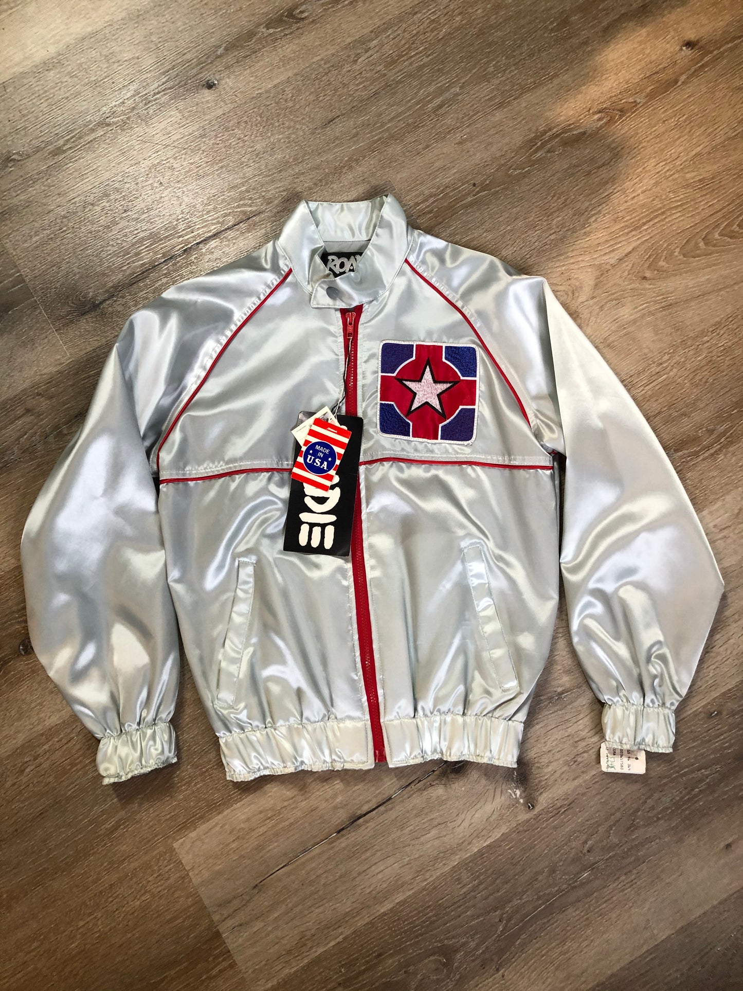 Kingspier Vintage - Milk and Honey - John Lennon and Yoko Ono Roadie Tour Jacket from the mid 1980’s. A very rare collectors piece from John Lennon’s last studio album. Jacket is light grey nylon with satin effect with two slash pockets, elastic waist and cuffs, chunky red zip up front with popper at the collar. The jacket features a star logo on the front and Milk and honey logo on the back with a rainbow. Made in the USA. Size XS.