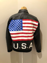 Load image into Gallery viewer, Kingspier Vintage - Two Plus Two black leather jacket with red and white details, large American flag on the back with USA written across the bottom. Slash pockets zipper closure, one inside pocket, nylon lining, knit cuffs and trim.

