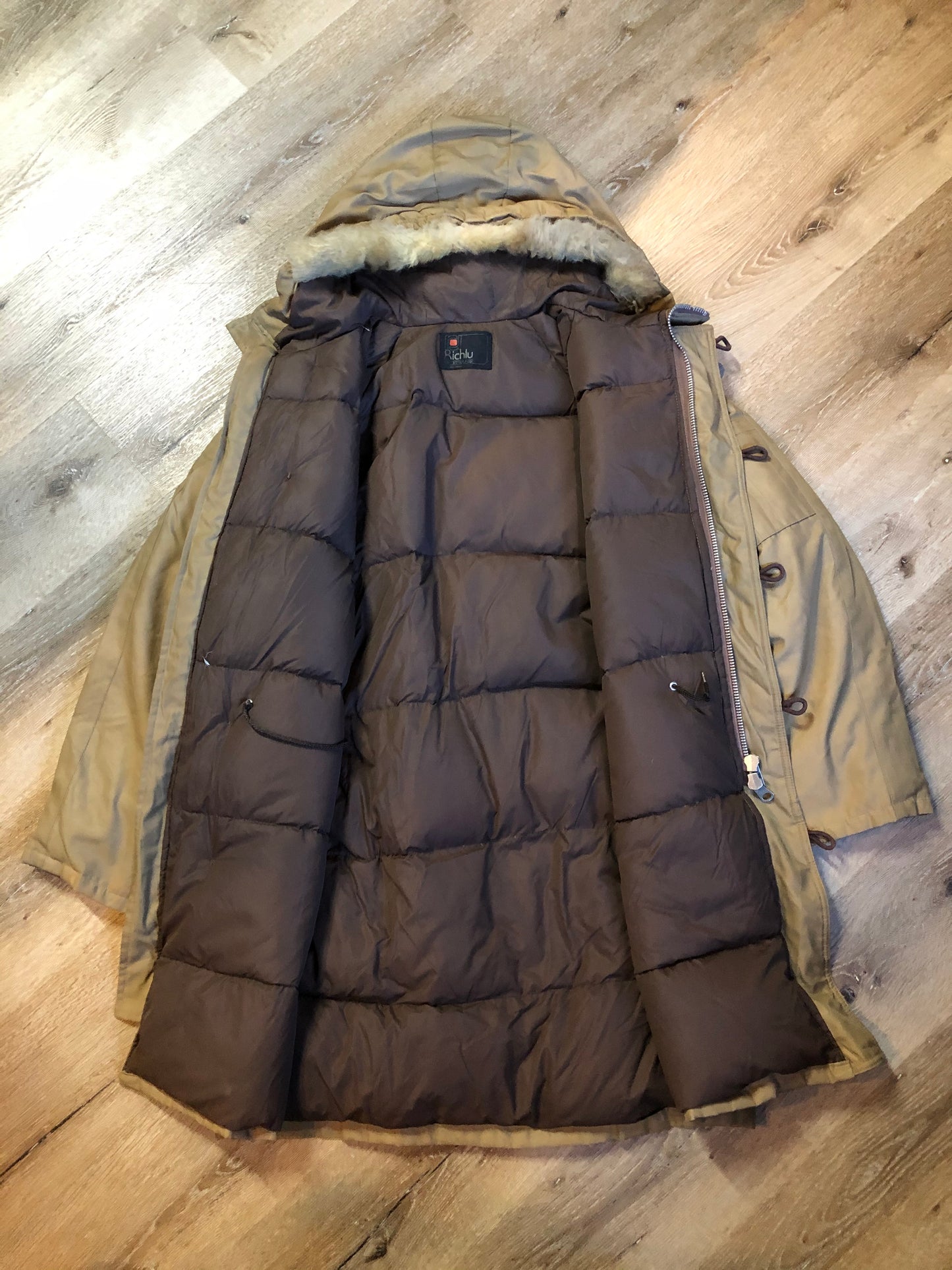 Kingspier Vintage - Richlu down-filled parka in beige with zipper and button closures, fox fur trimmed hood for exceptionally cold conditions. This parka has leather reinforcement details, two flap pockets and two hand warmer pockets with knit inside cuffs and inside drawstring. Made in Winnipeg, Canada. Size large.