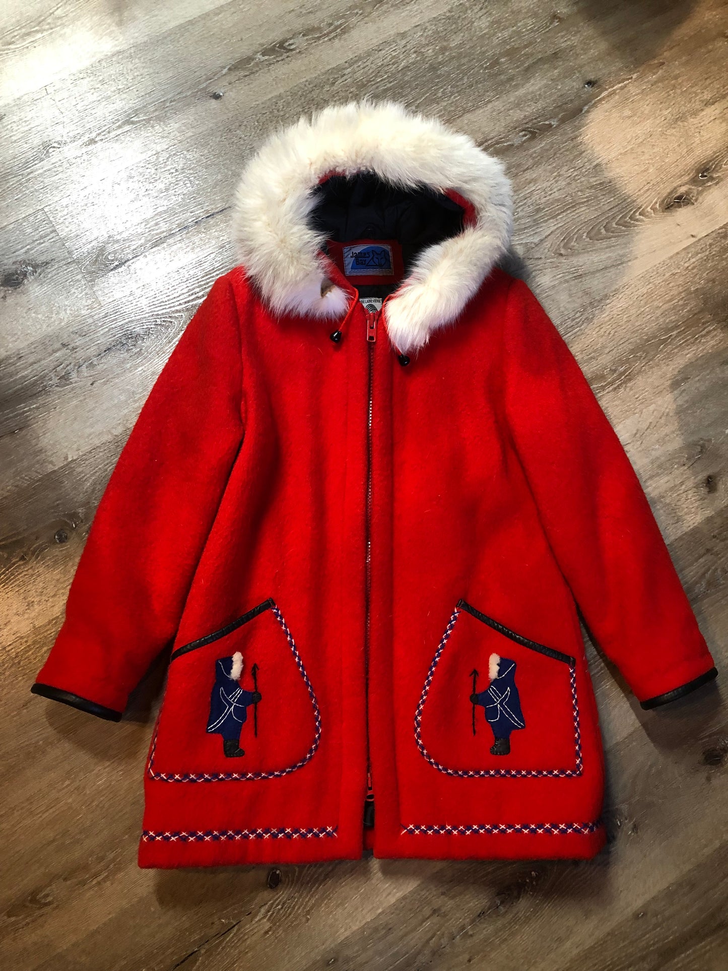 Vintage James Bay 100% virgin wool northern parka in bright red. This parka features a white fur trimmed hood, zipper closure, patch pockets, quilted lining, storm cuffs, embroidery details and northern fishing scene in felt applique. Made in Canada - Kingspier Vintage